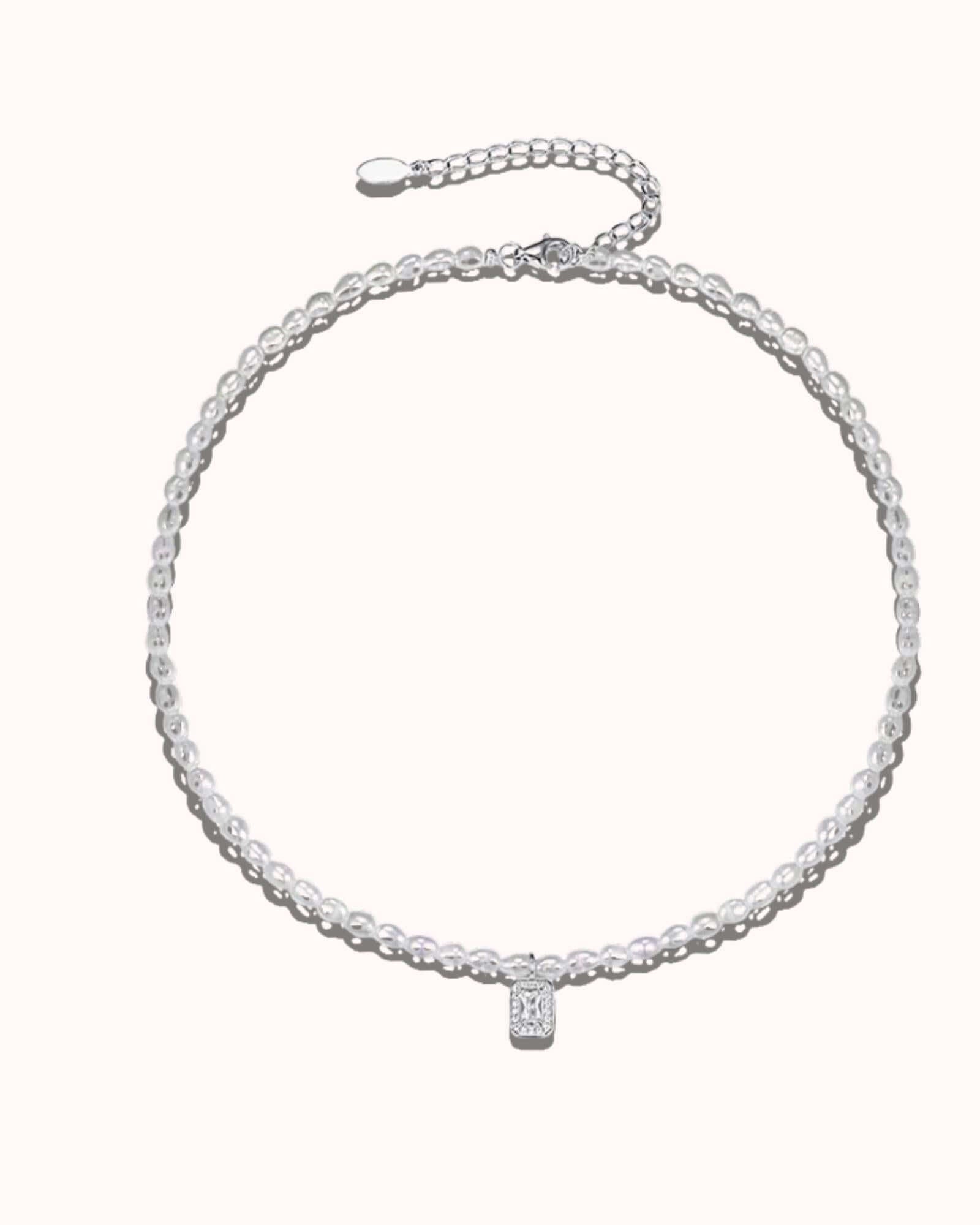 Silver necklace with a small pendant on a white background