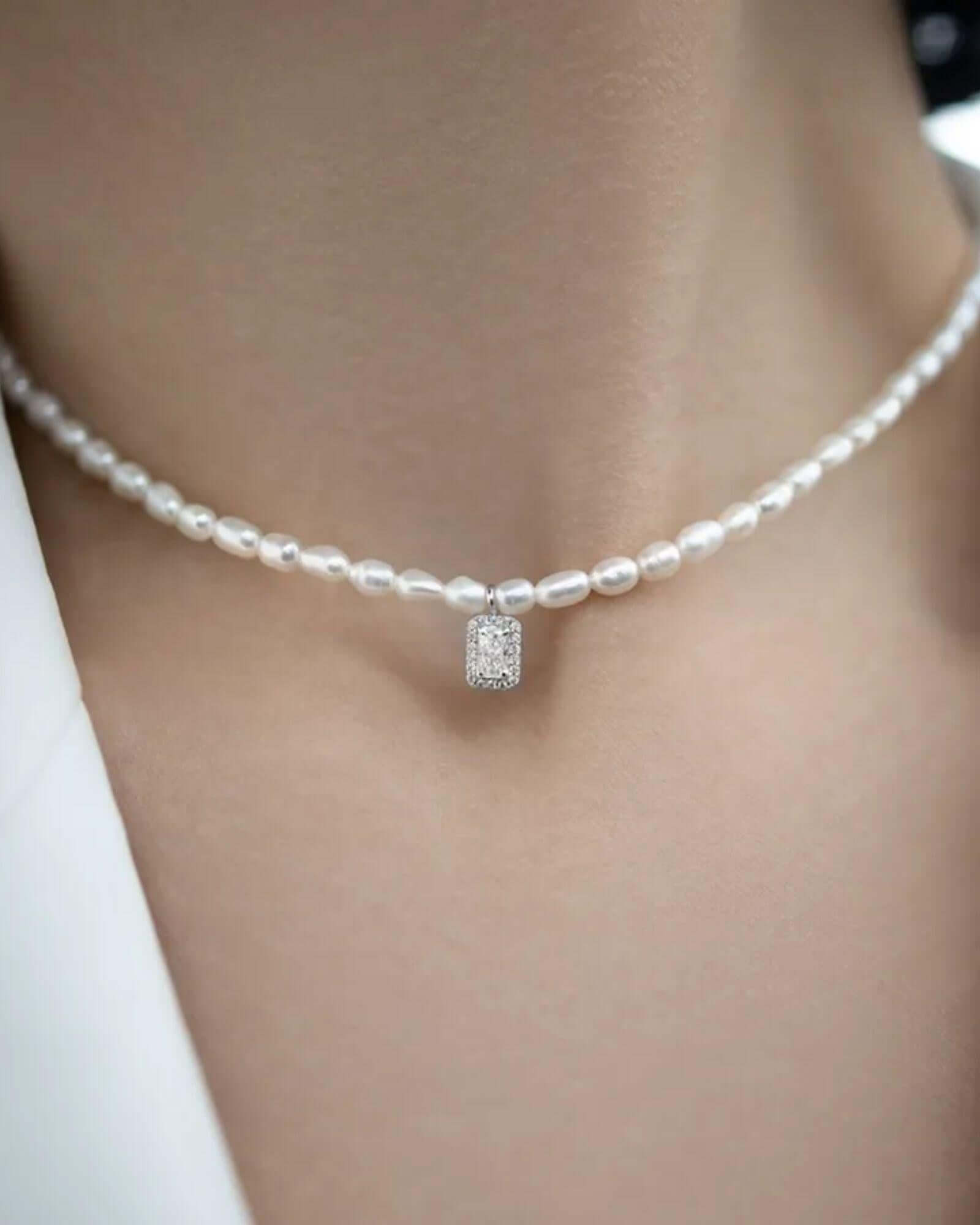 Pearl necklace with a diamond pendant on a neutral background