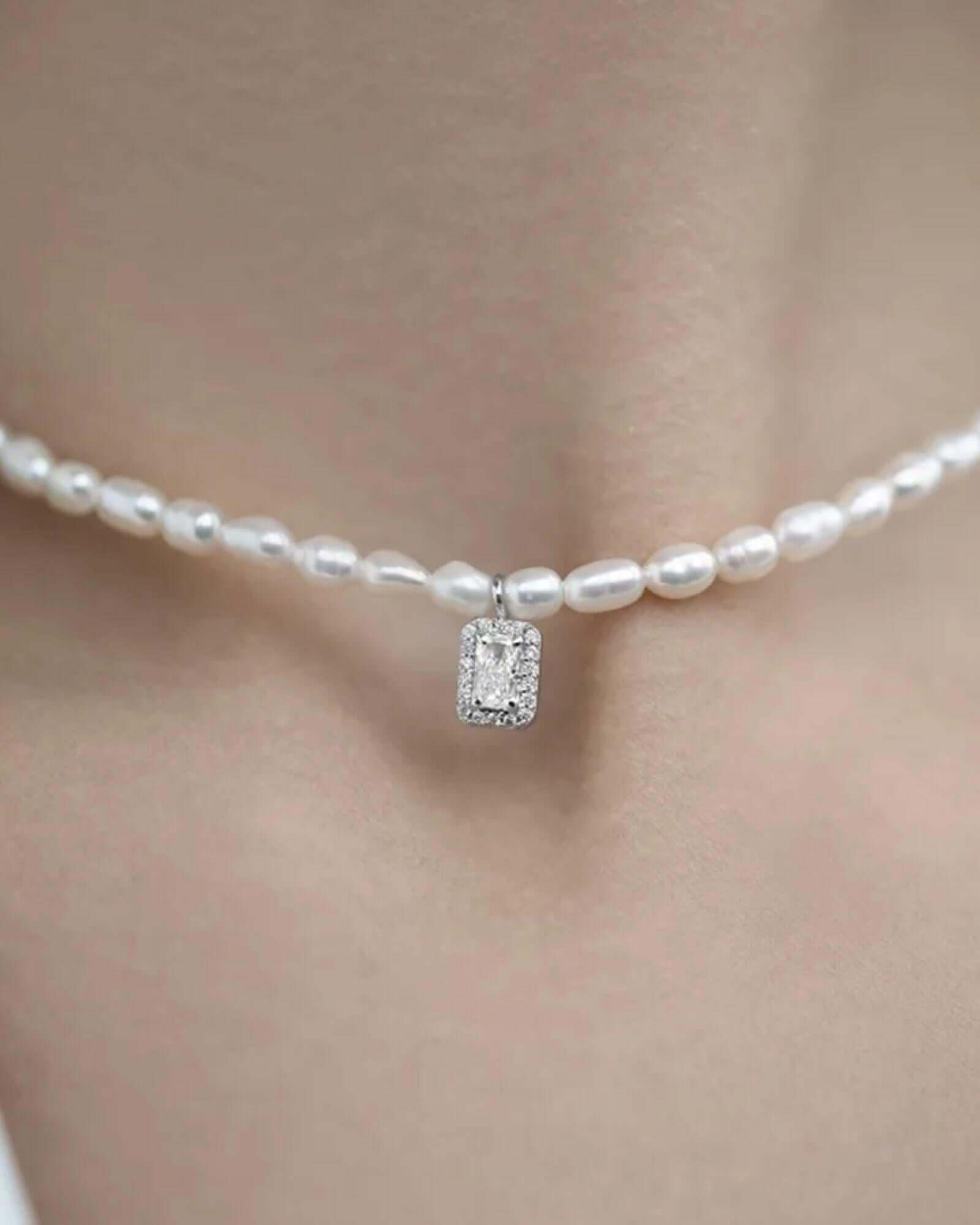 Pearl necklace with a diamond pendant on a blurred background
