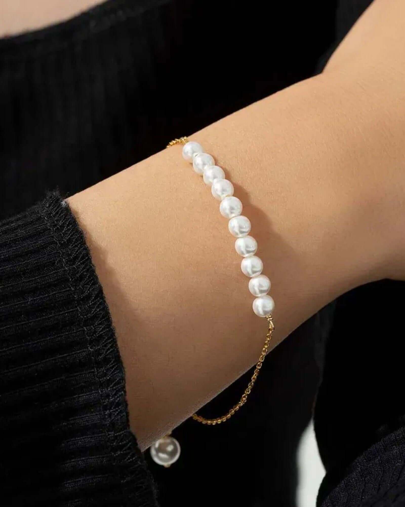 Pearl bracelet on a wrist with a black background