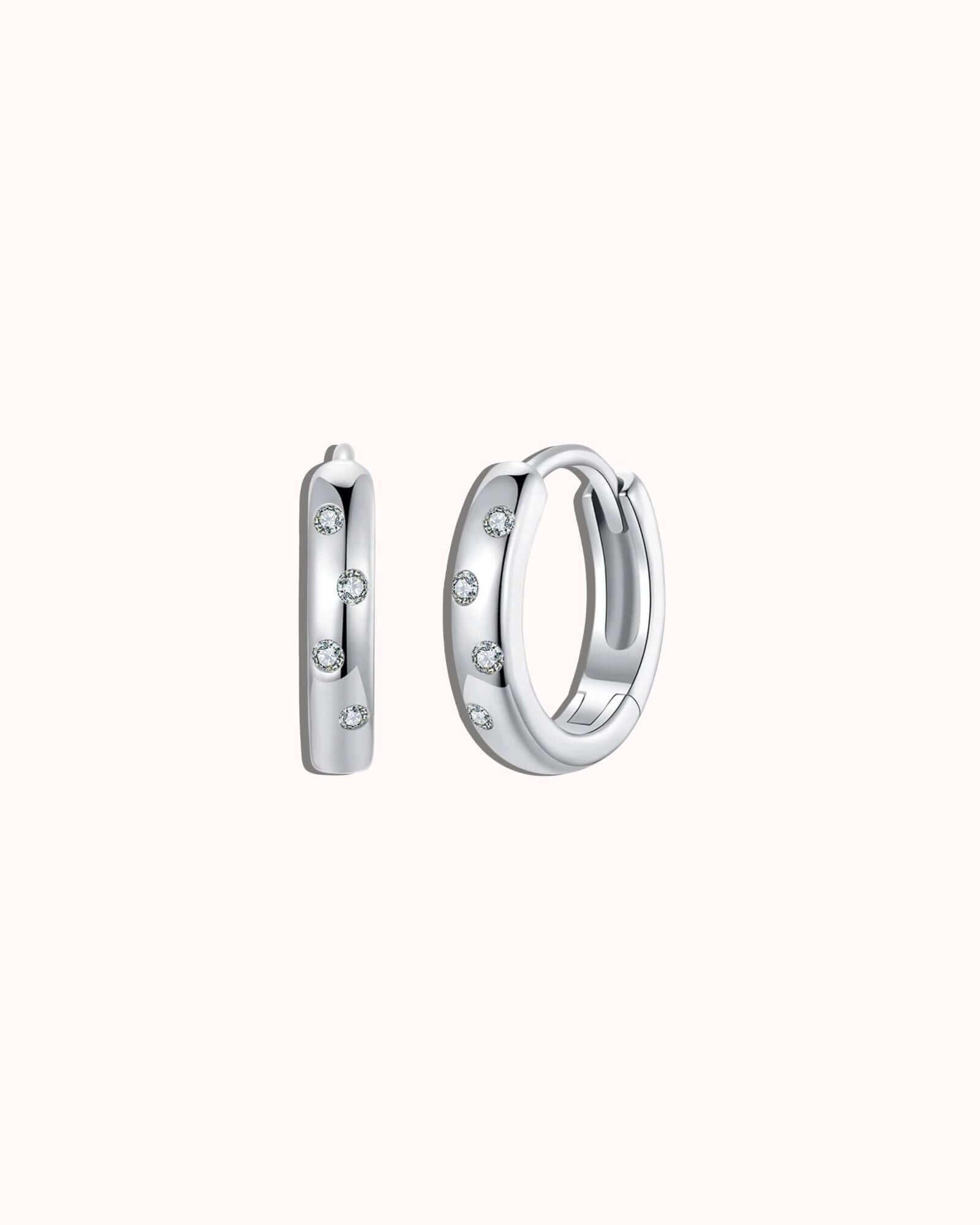 Silver hoop earrings with small stones on a white background