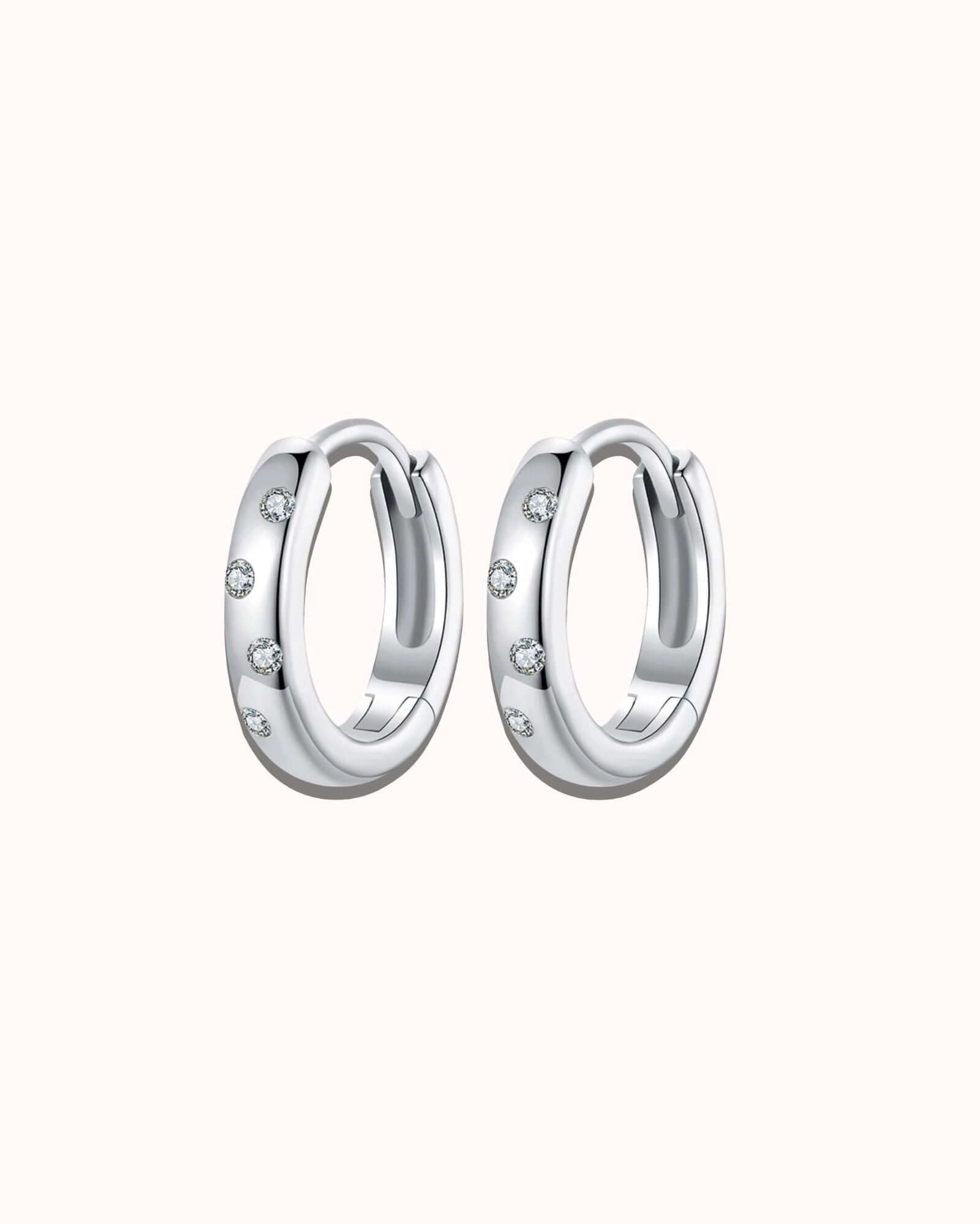Pair of silver hoop earrings with small stones on a white background