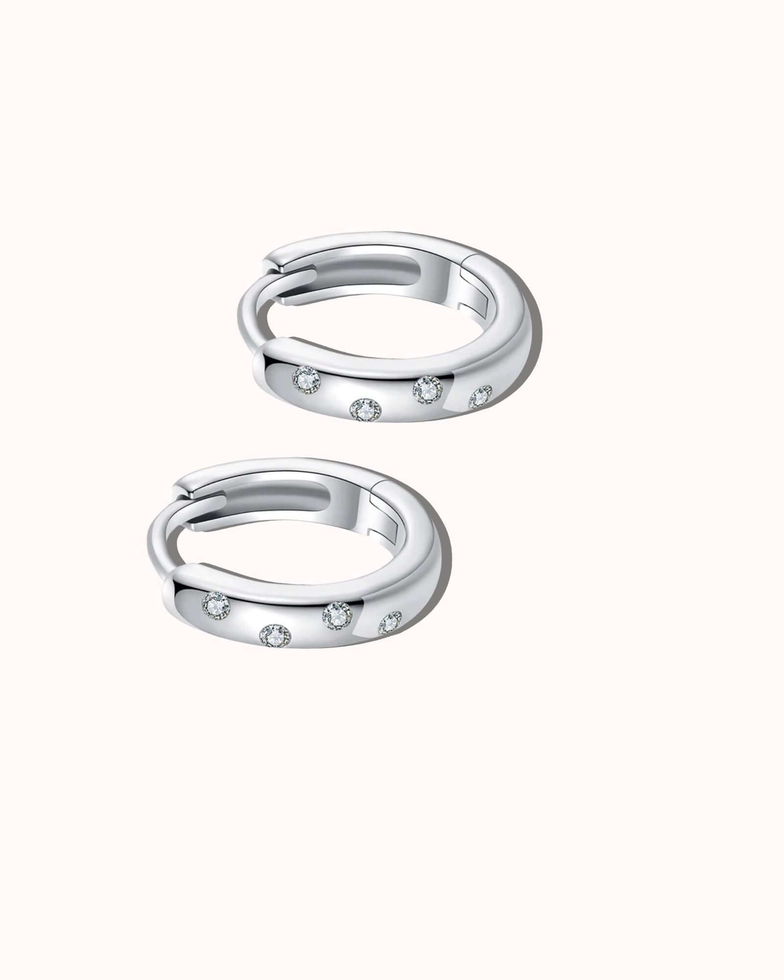 Pair of silver hoop earrings with small stones on a white background