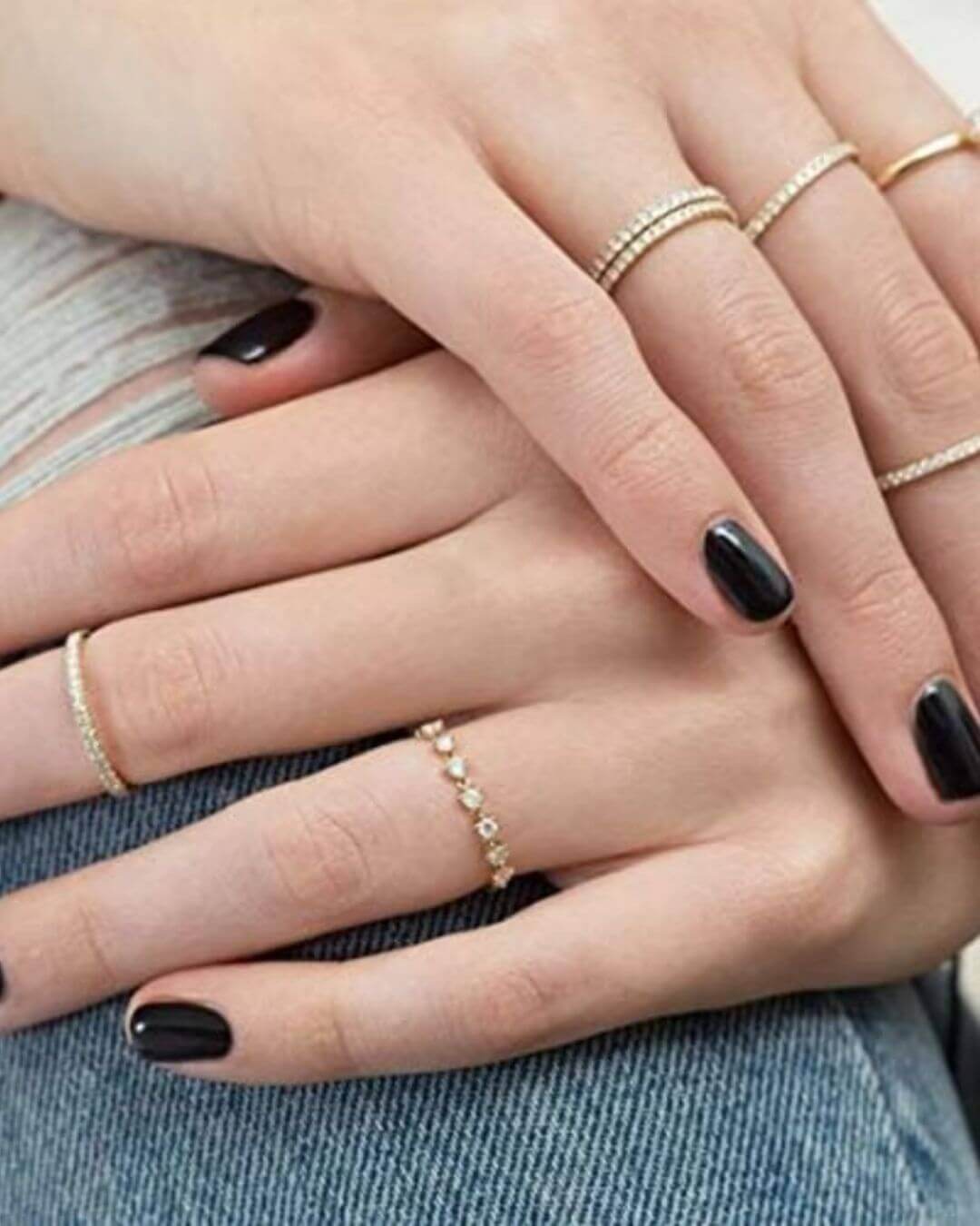 Close-up of a hand adorned with multiple half eternity stackable rings in gold, showcasing stylish jewelry ensemble.