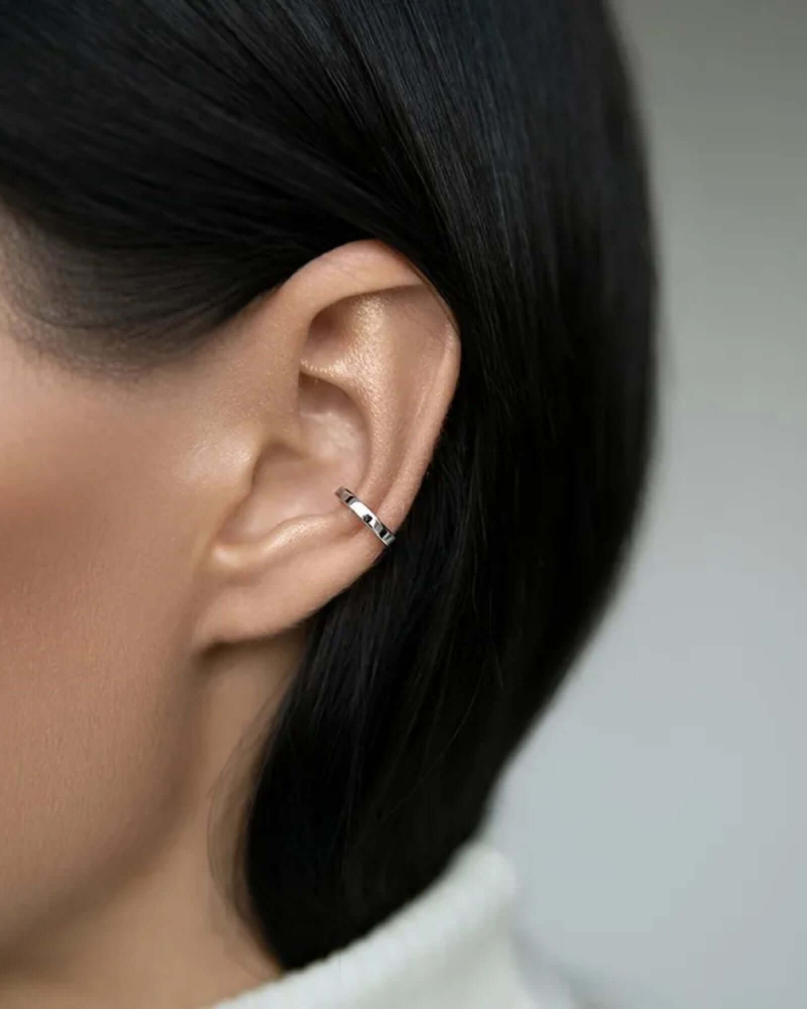 Silver ear cuff on a model’s ear showcasing non-piercing design and sleek styling.