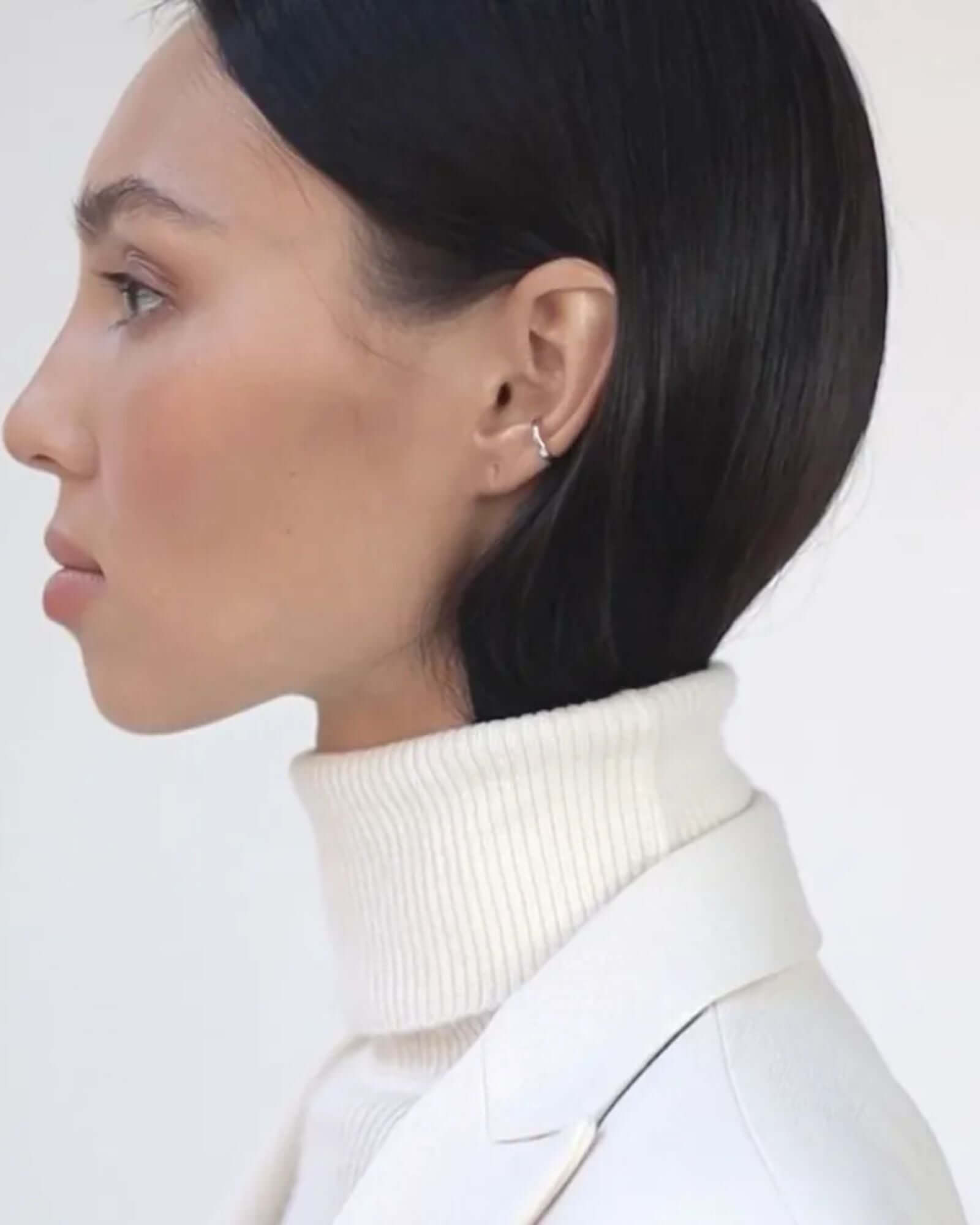 Profile view of a model wearing a silver ear cuff showcasing its sleek design and non-piercing style.
