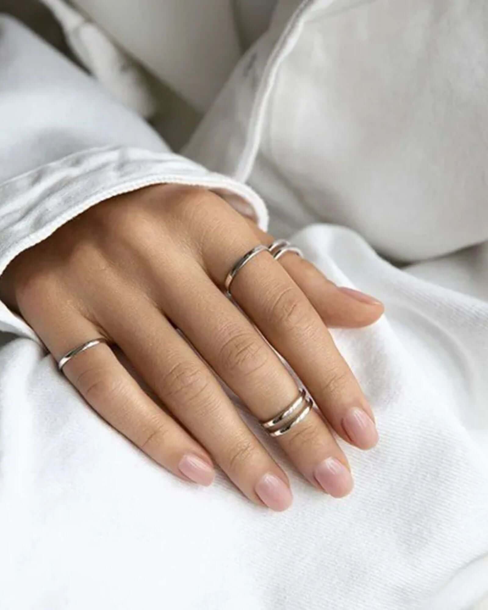Plain silver ring displayed on a hand with minimalist silver rings, showcasing timeless elegance in simplicity.