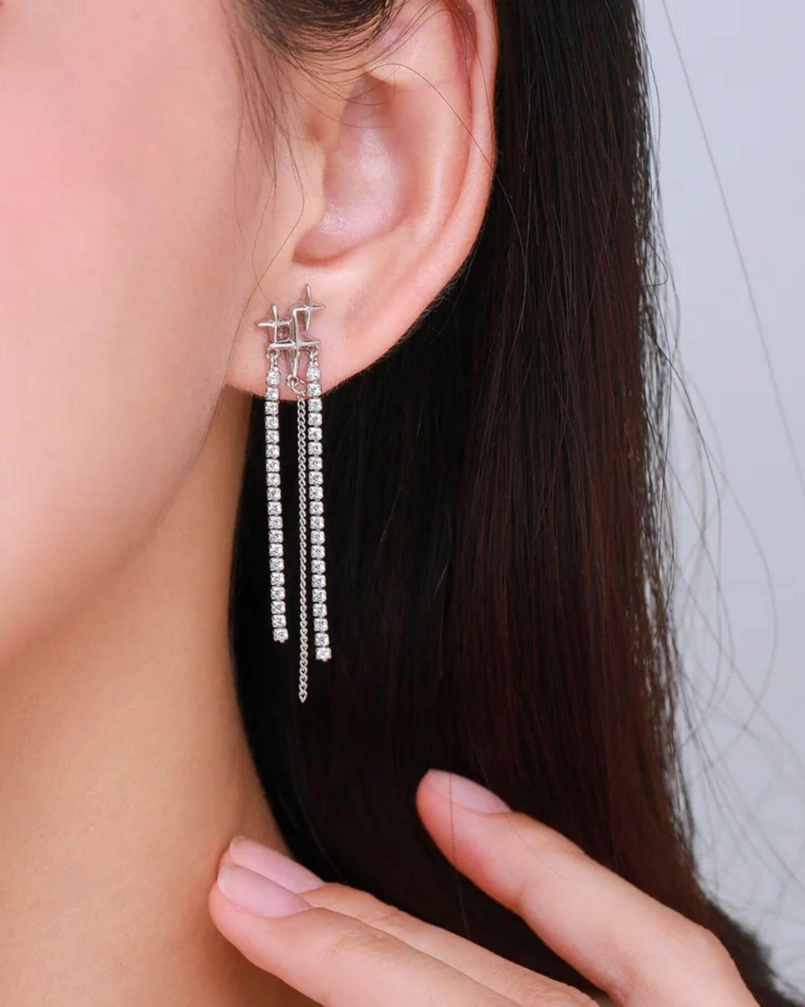 Close-up of a person wearing silver tassel earrings, showcasing sleek design and elegant shine.
