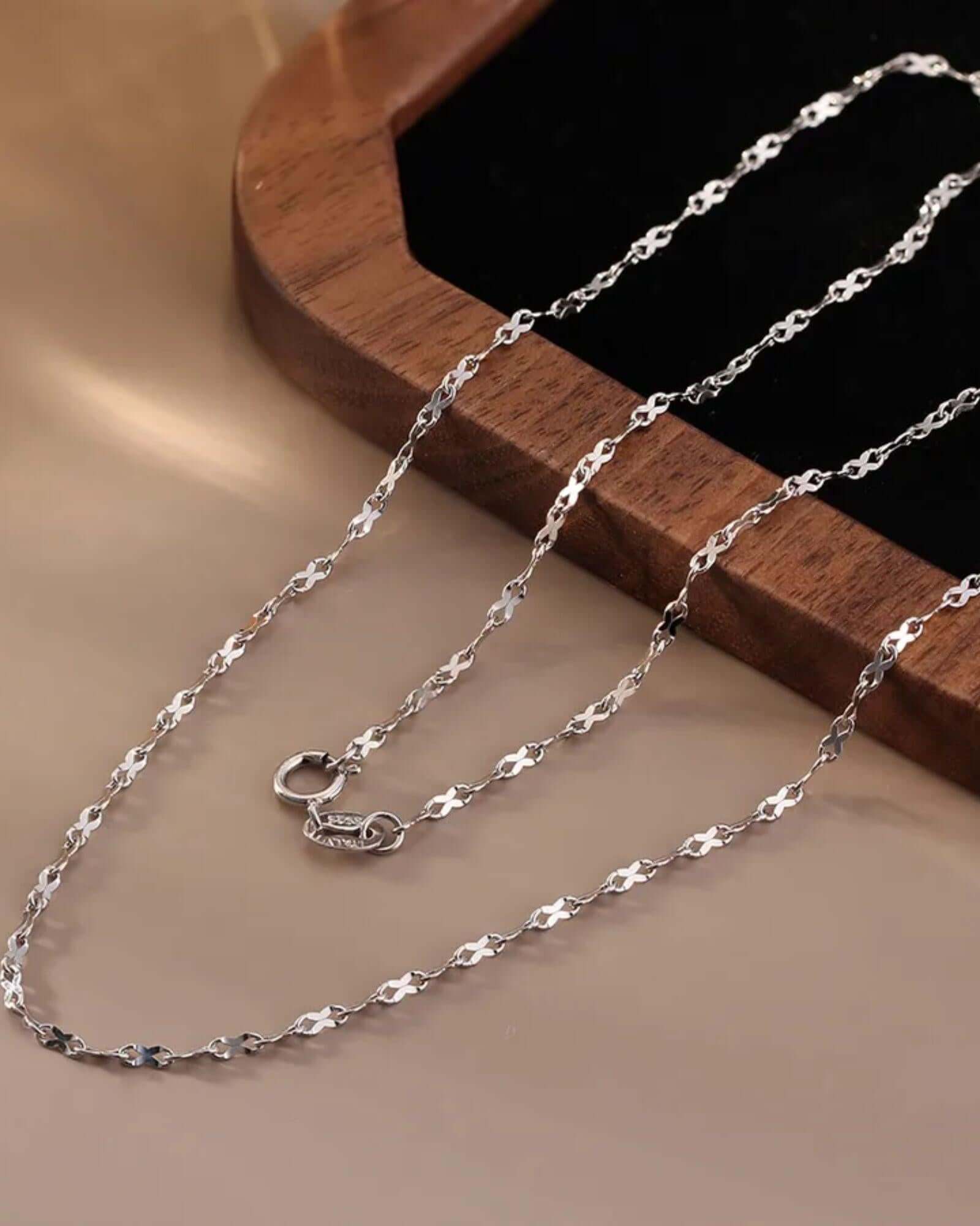 simple figure eight chain in sleek silver finish with secure clasp on a wooden surface.