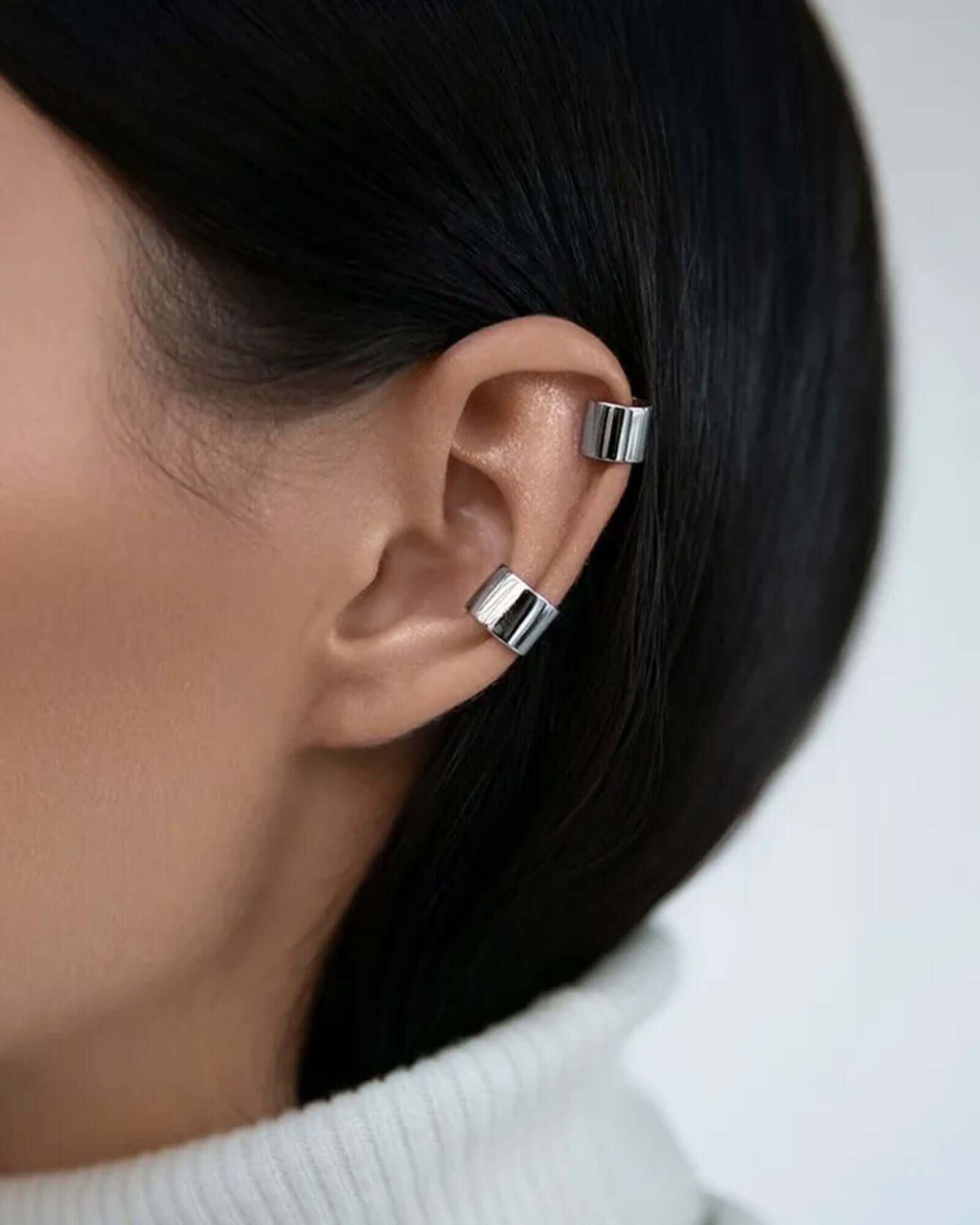 Close-up of a person wearing silver ear cuff with a neutral background