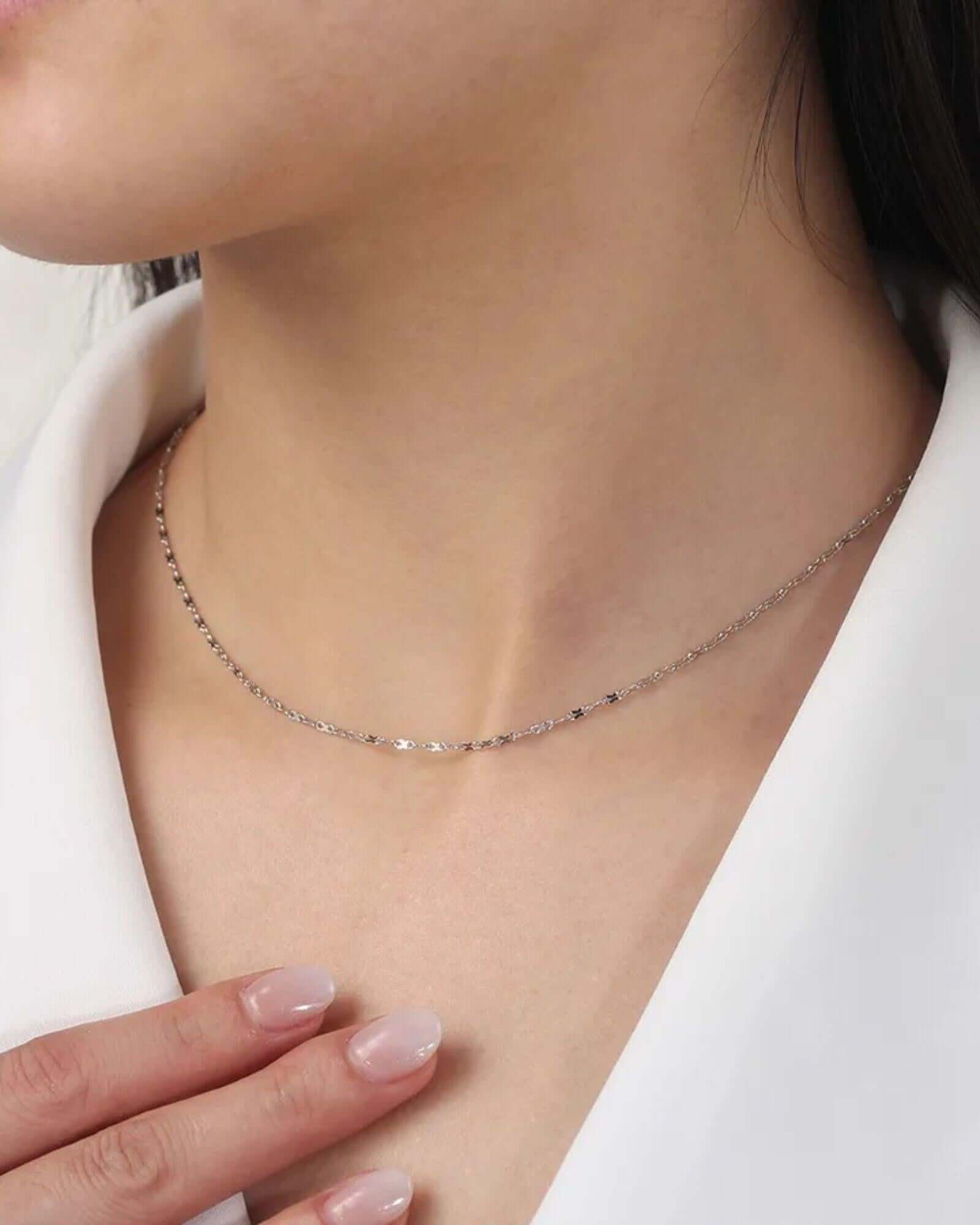 Simple figure eight chain in silver worn on the neck, showcasing its sleek design and elegant finish.