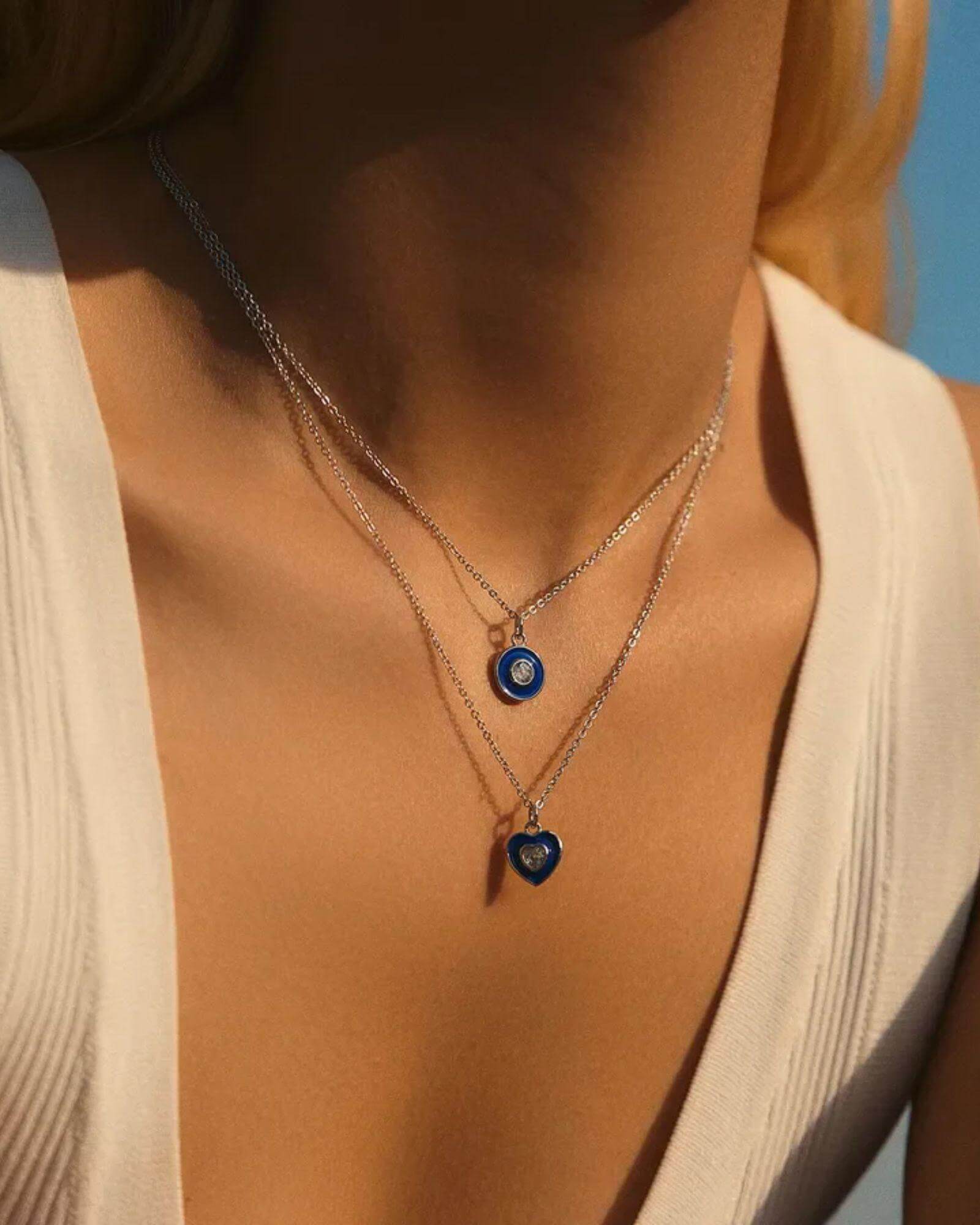 Heart Devil's Eye Pendant necklace displayed on a model wearing a cream top, featuring blue and silver accents.