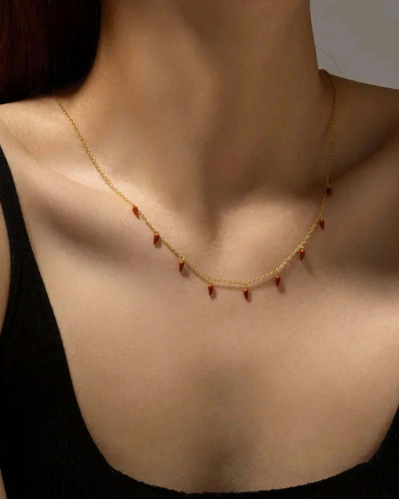 Close-up of the Spicy Bloom Chilli Charm Necklace featuring delicate chilli charms on a gold chain.