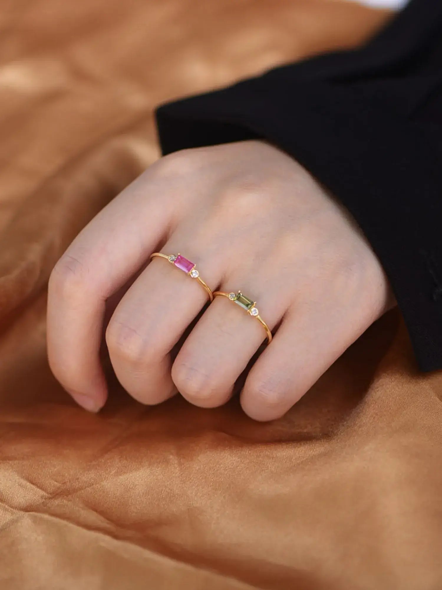 Close-up of hands wearing Viola Rings with ruby red and olive green stones, set in 18k gold over sterling silver.
