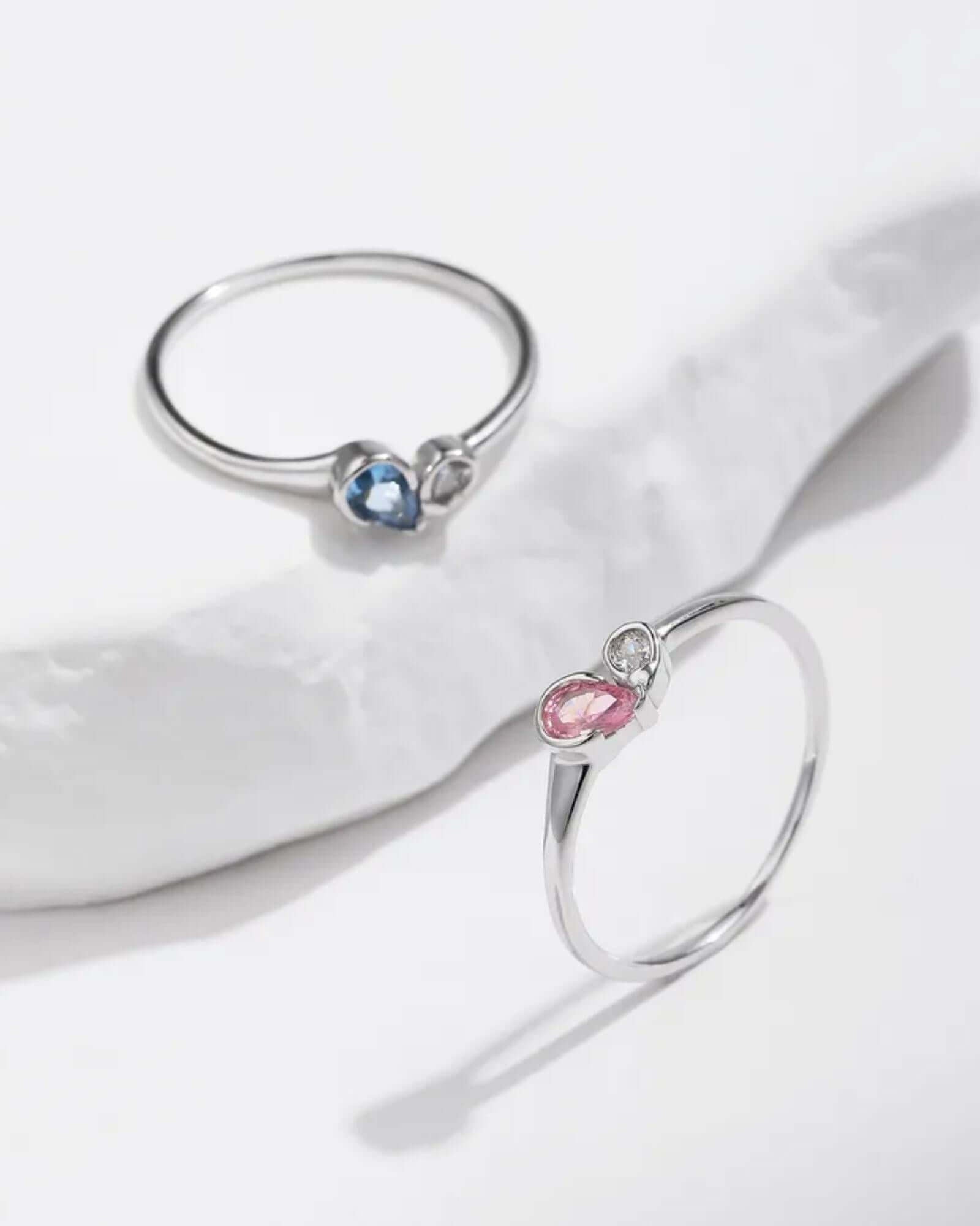 Two silver rings with gemstones on a white surface