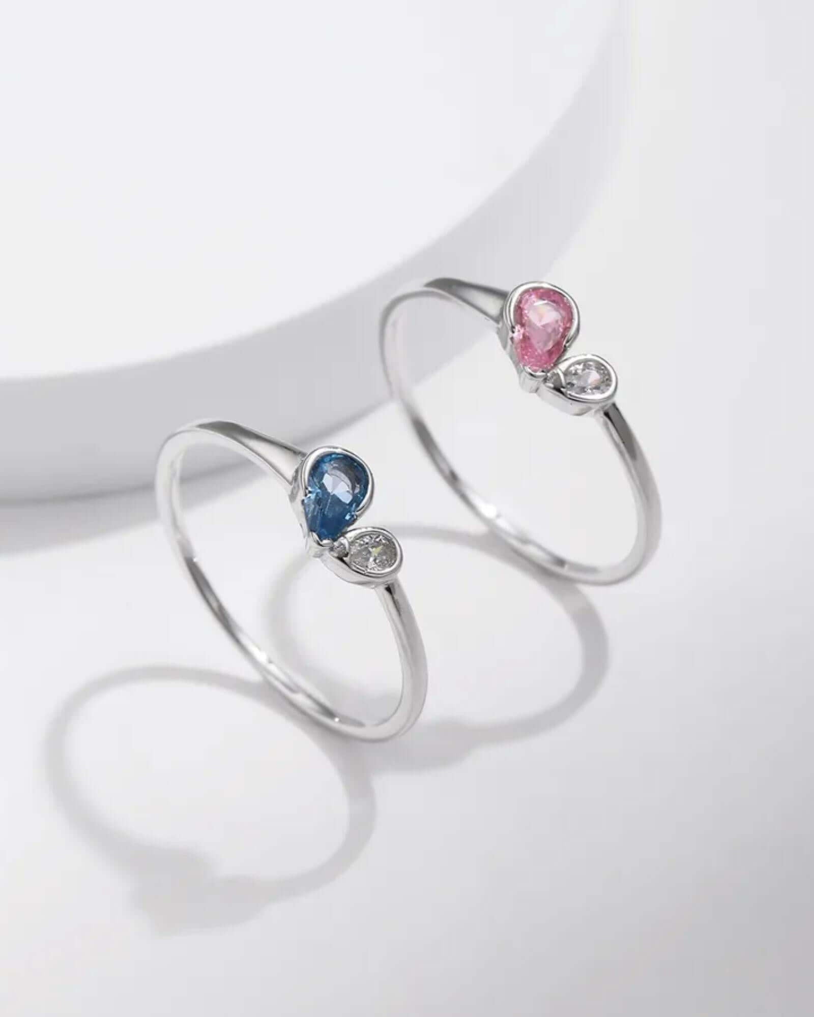 Two silver rings with gemstones on a light gray background