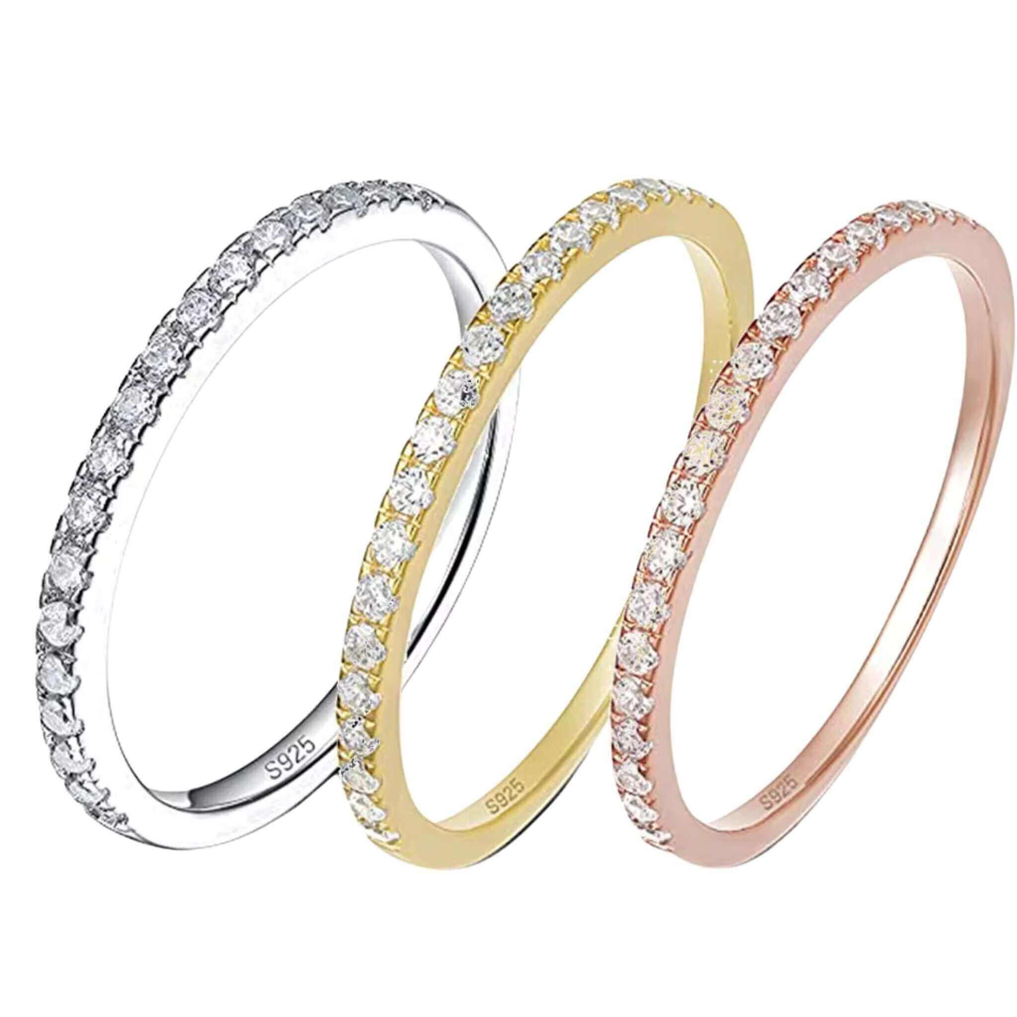 Three half eternity stackable rings in gold, silver, and rose gold with bezel-set zircons on a sleek sterling silver band.