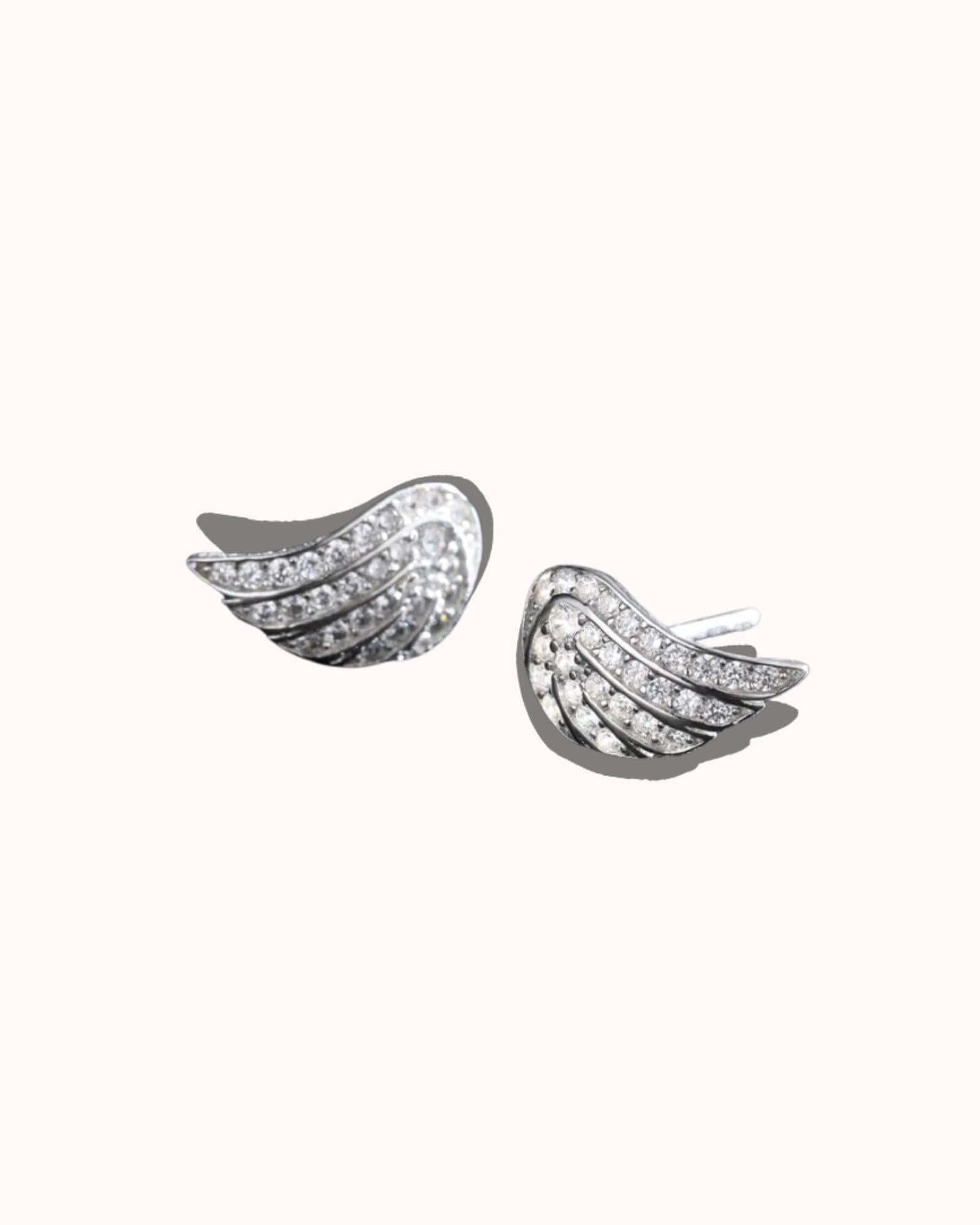 Pair of silver wing-shaped earrings on a white background