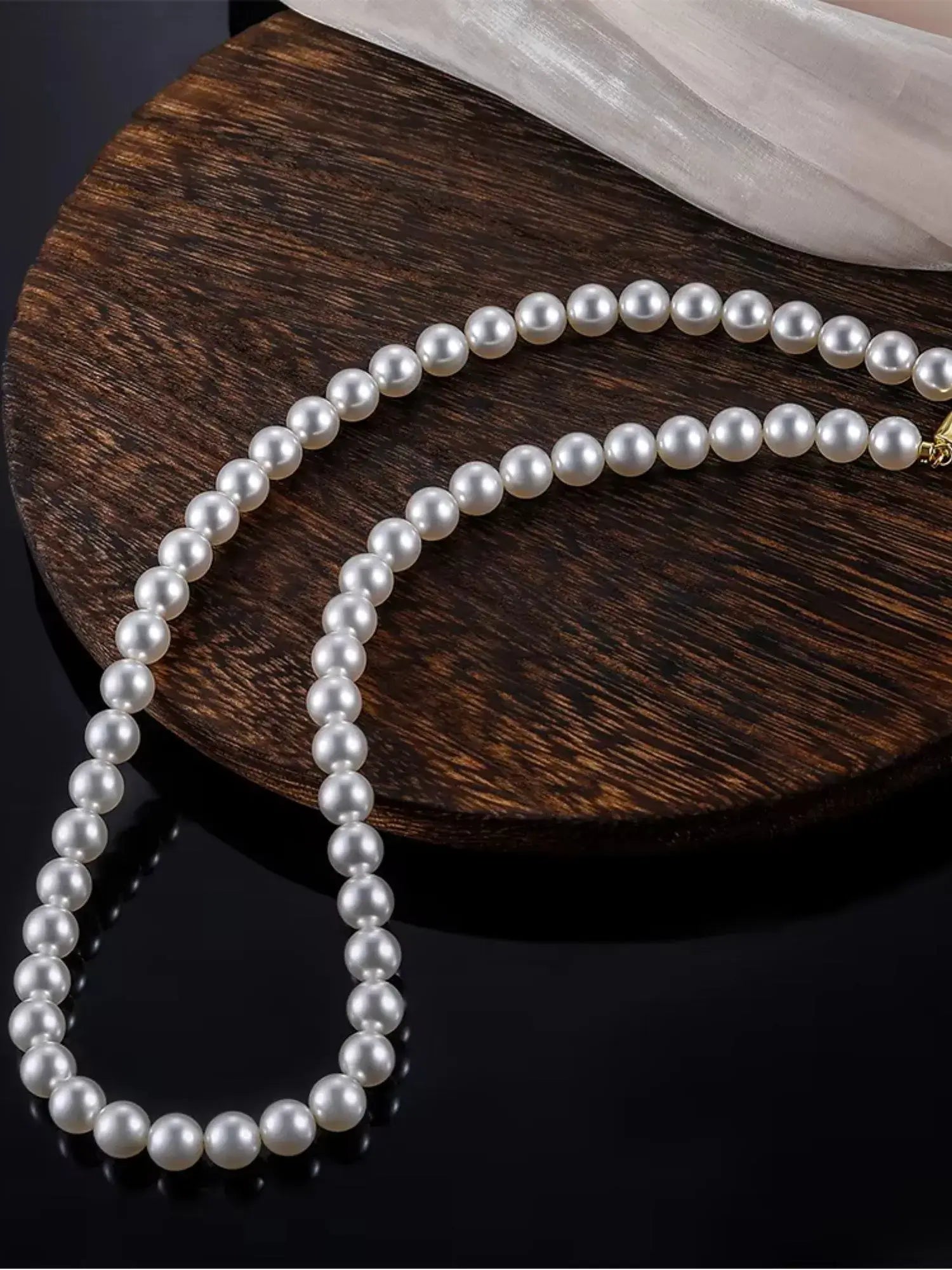 Elegant White Pearl Vintage Choker Necklace on a wooden surface, showcasing lustrous pearls and a timeless design.