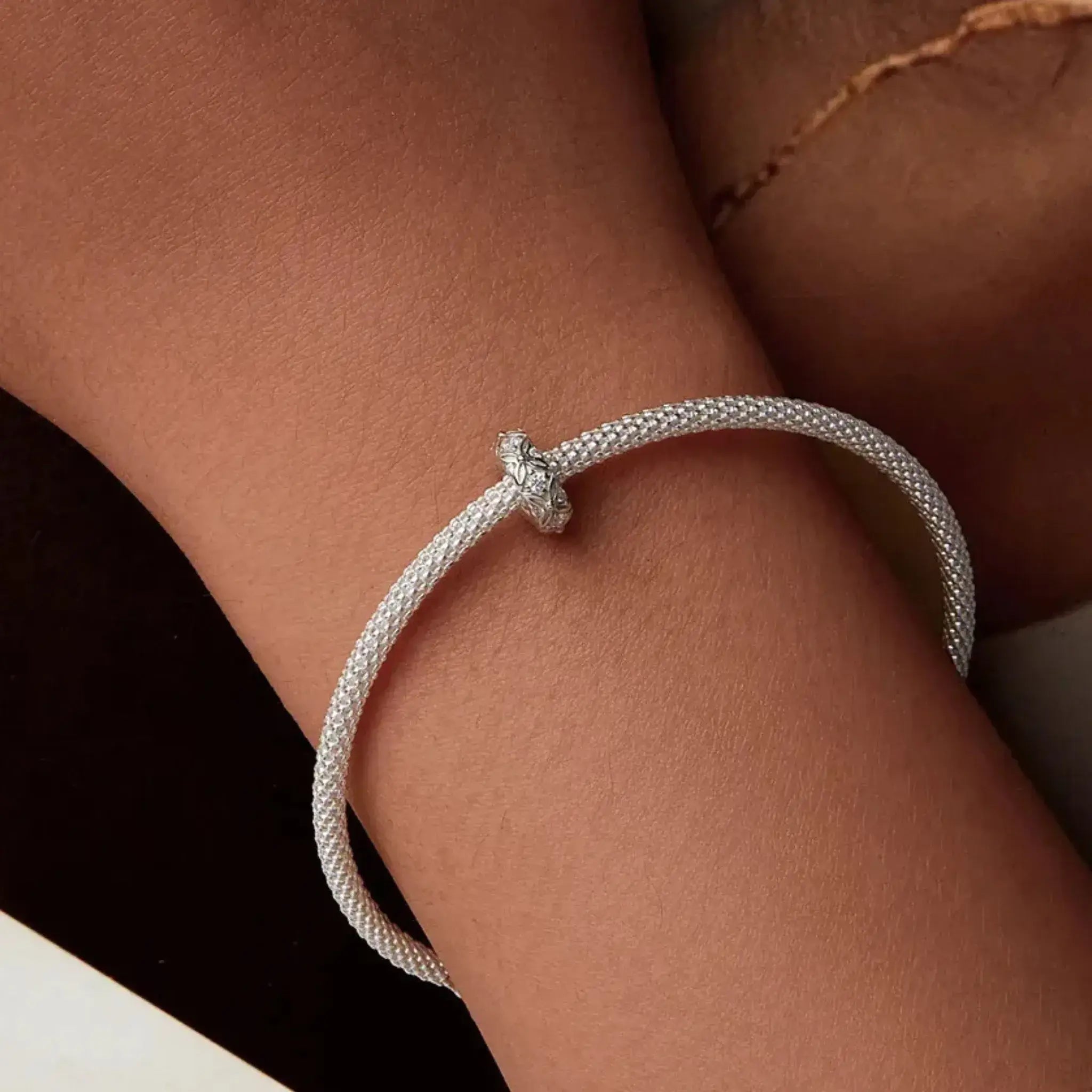 Silver bracelet on a wrist with a neutral background
