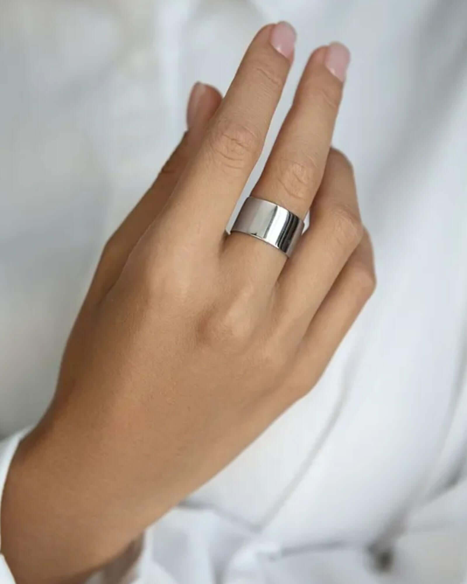 Hand wearing a silver ring on a plain background