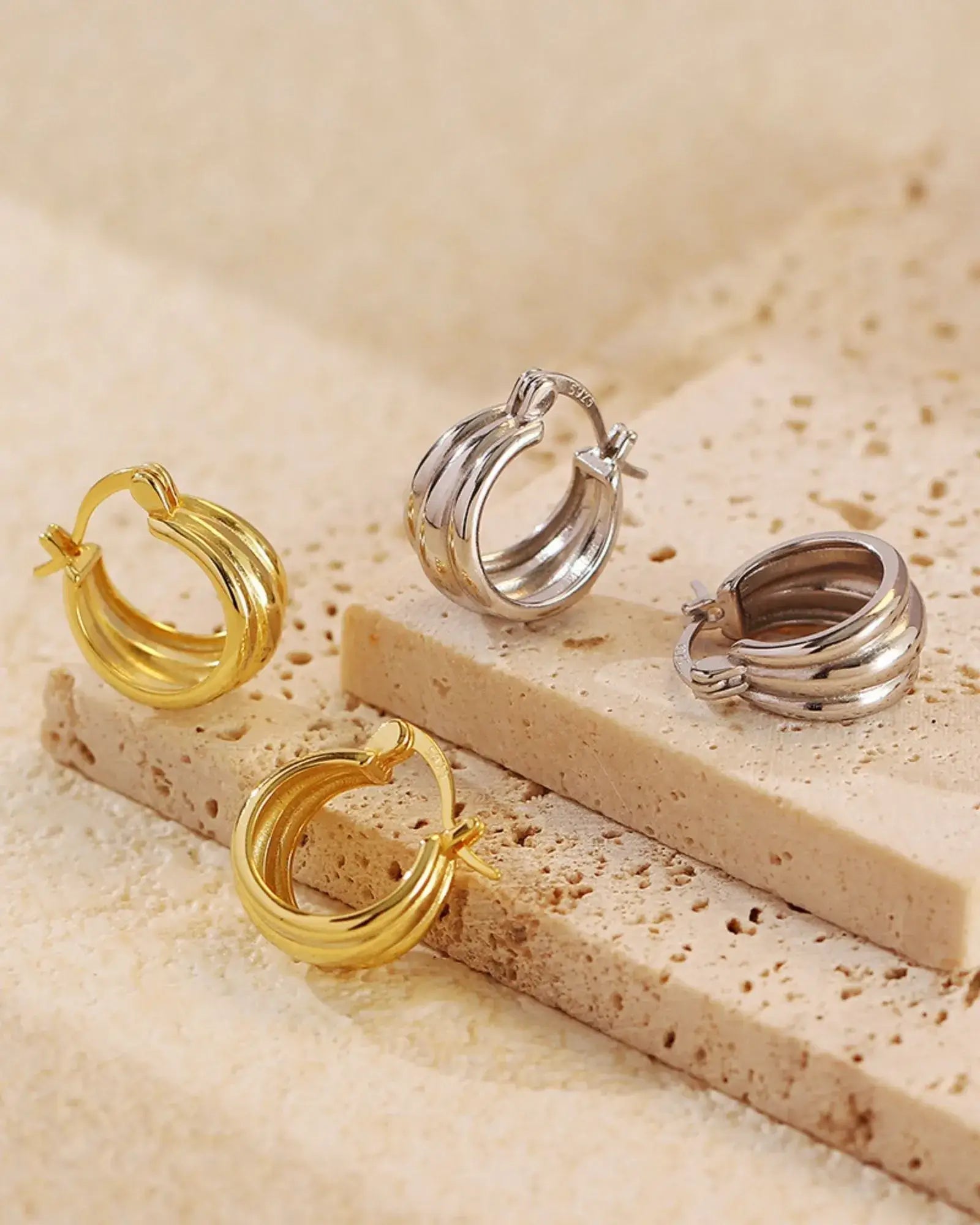 Aura Curve Hoop Earrings in gold and silver, showcasing a sleek sculptural design, perfect for any jewelry lover.