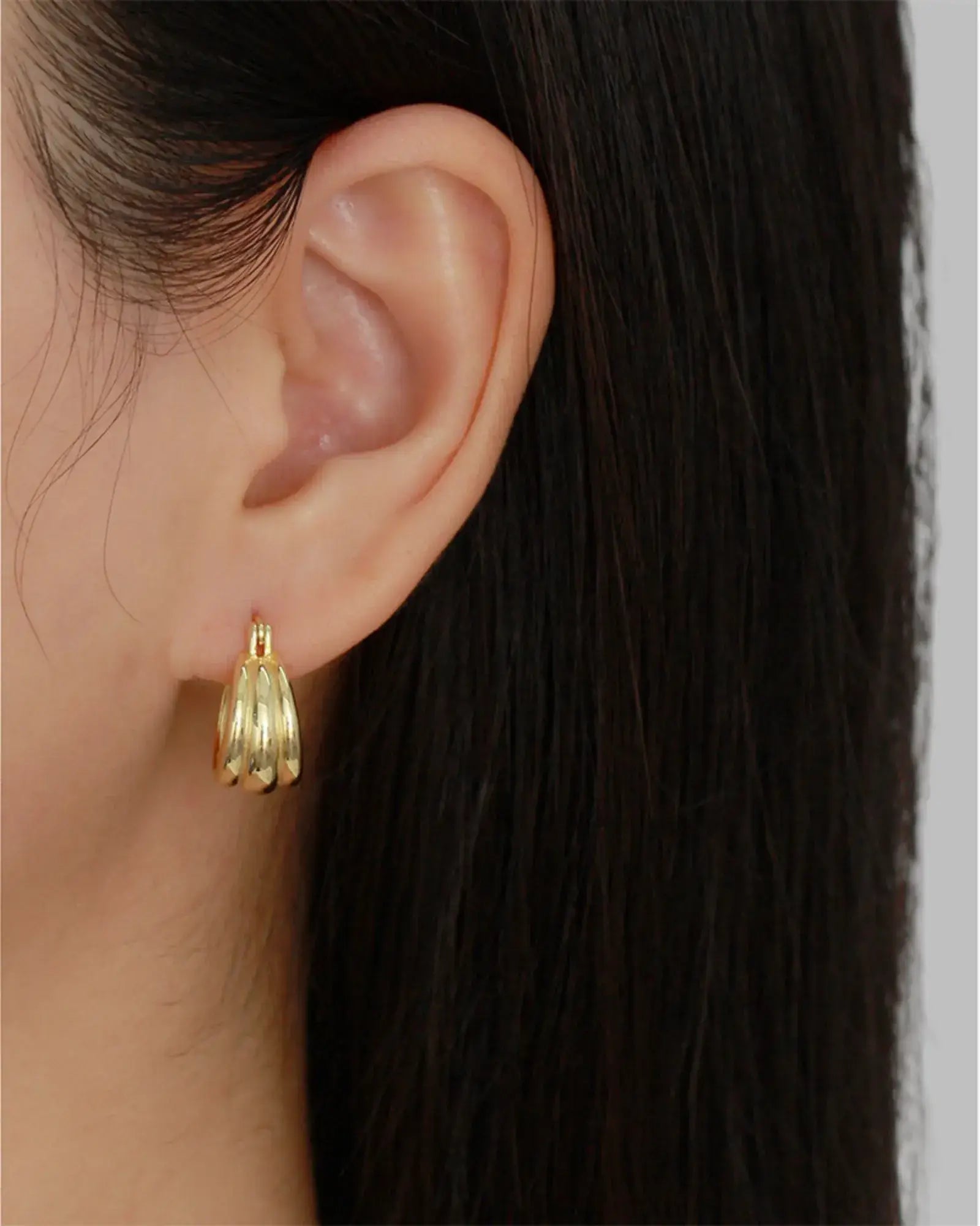 Aura Curve Hoop Earrings in gold, showcased on model, highlighting their sculptural design and light-reflecting qualities.