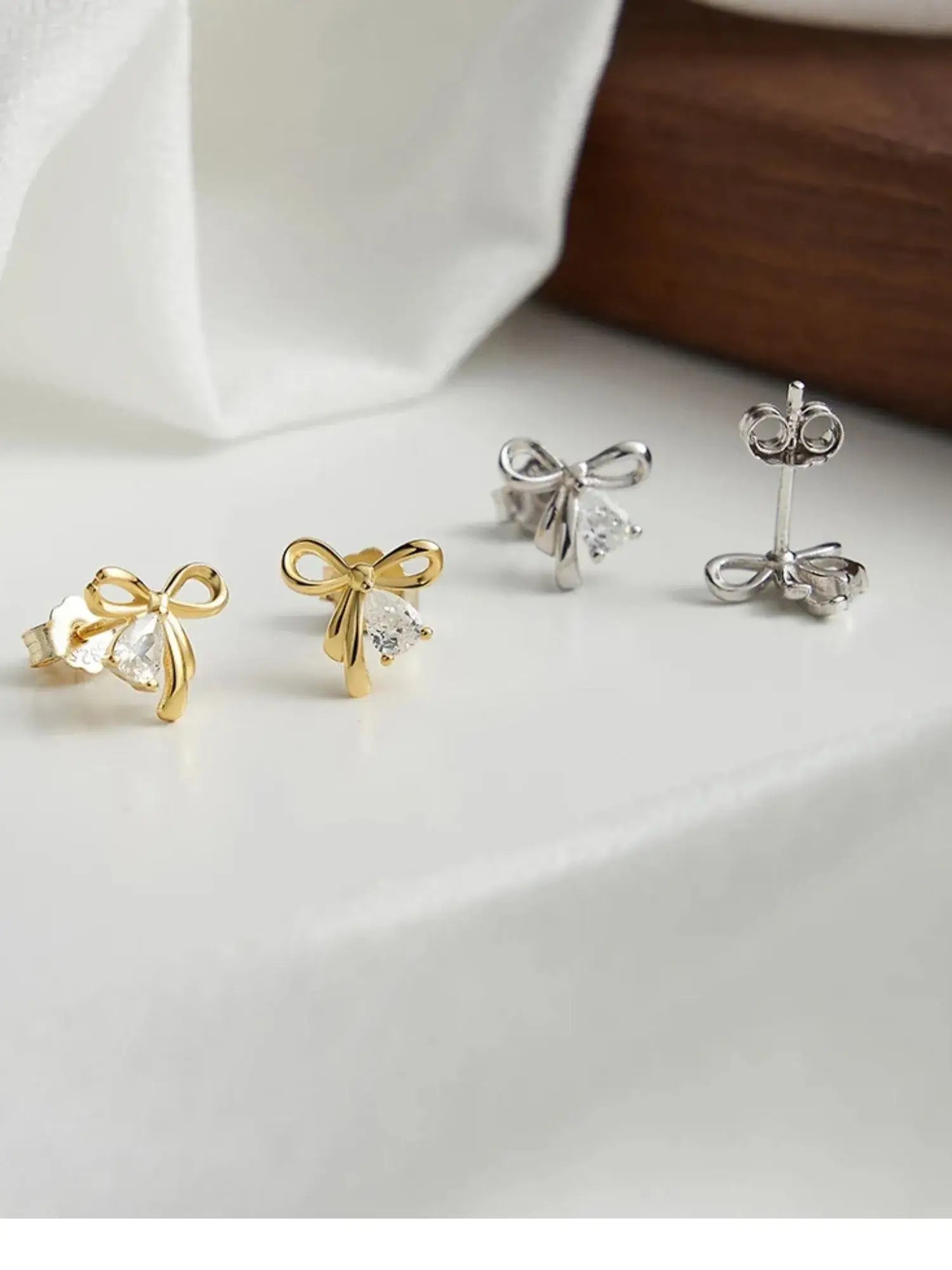 Bowknot stud earrings in gold and silver showcasing AAAAA zircon. Minimalist design for romantic everyday wear.