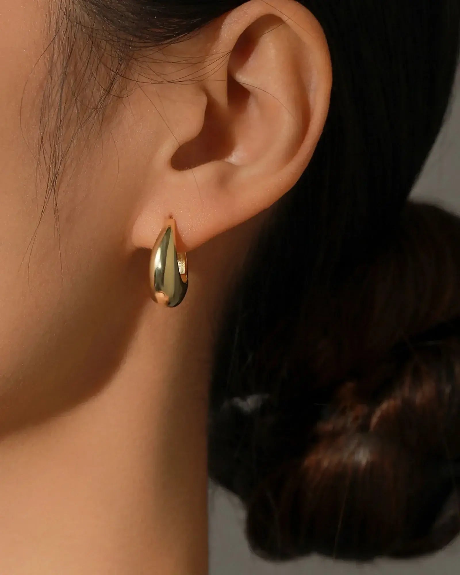 Close-up of a model wearing Irregular Solid Hoop Earring in 925 Sterling Silver, showcasing its unique shape and high-polish finish.