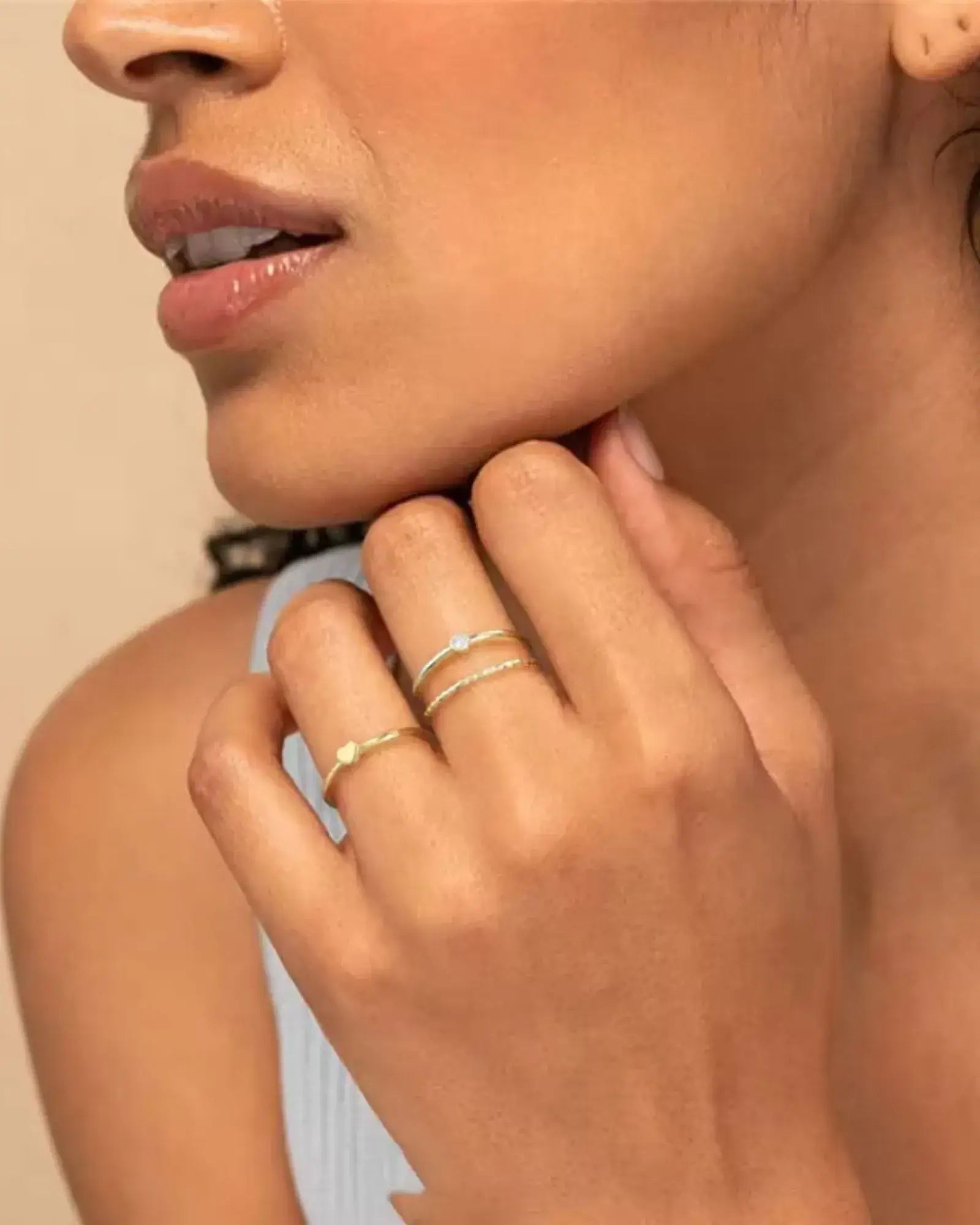 Elegant model showcasing Golden Whisper Rings in stacked arrangement, featuring gold plating and cubic zirconia details.