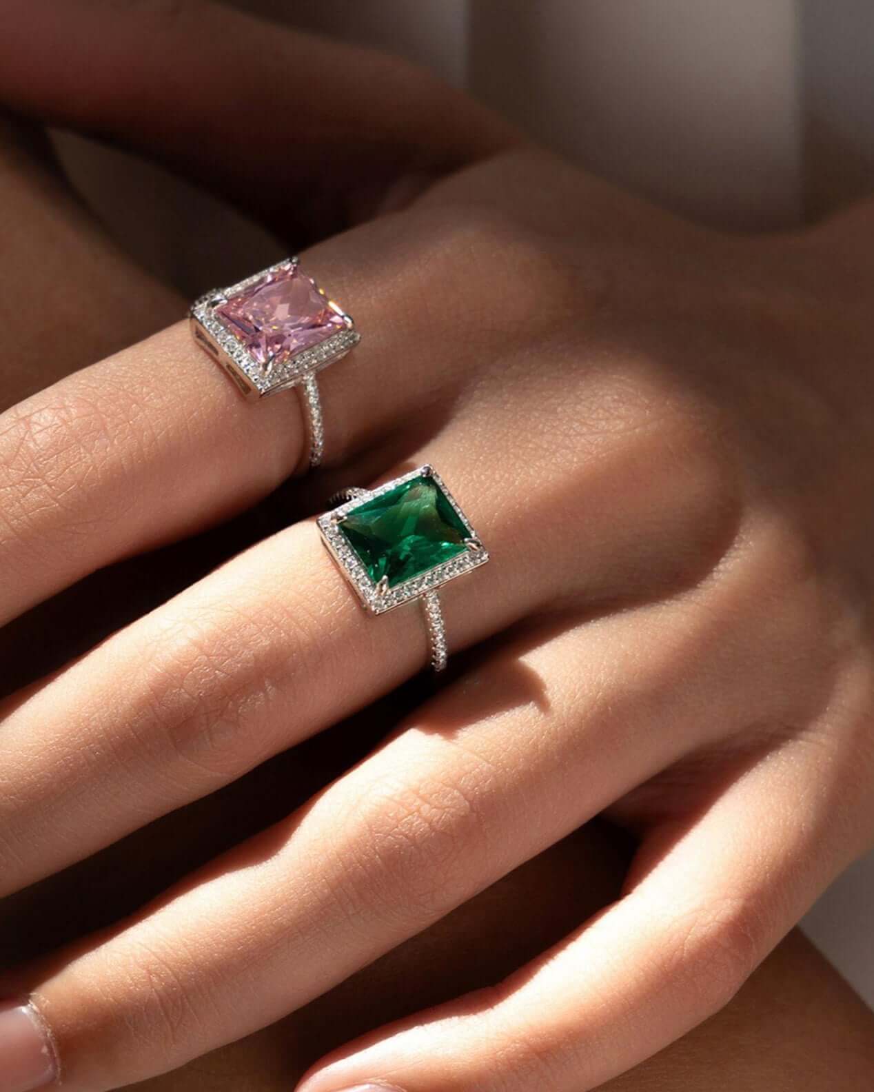 Green and pink zirconia cocktail rings set on hands, showcasing sterling silver bands and elegant gemstones.