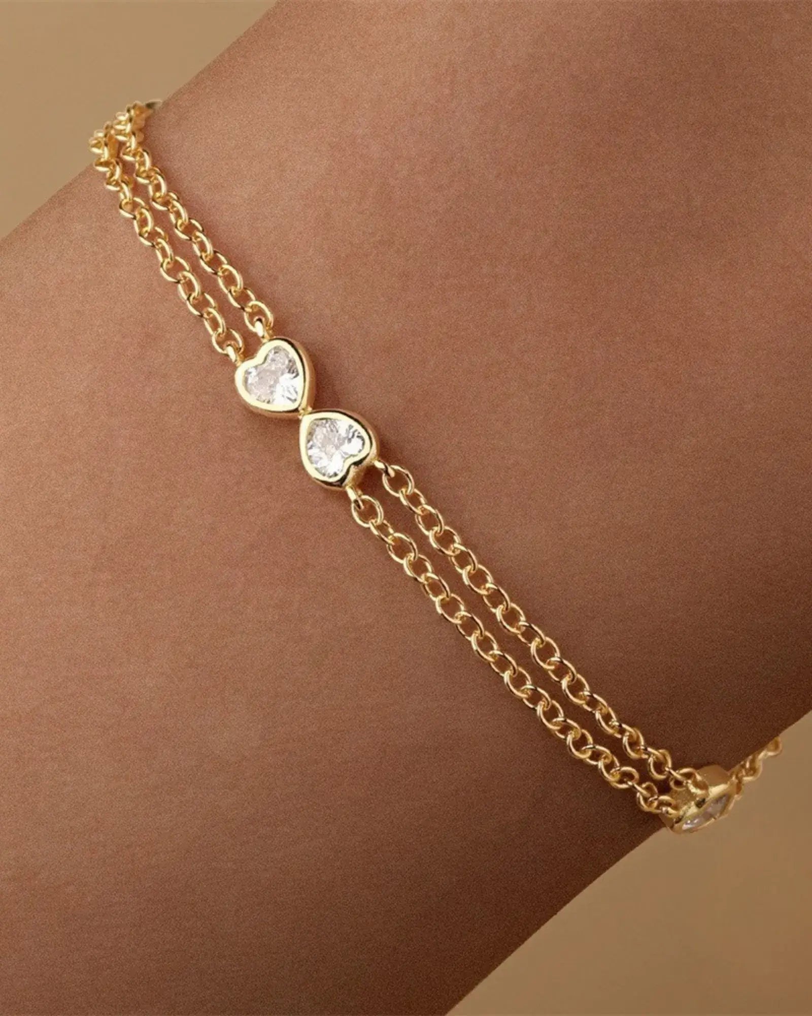 Heart Bow Bracelet in gold plating with sparkling cubic zirconia and dual cable chain design, perfect for any occasion.