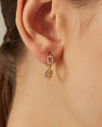 Close-up of a woman's ear wearing Hollow Chain Link Luxe Hoops with cubic zirconia accents and gold-plated design.
