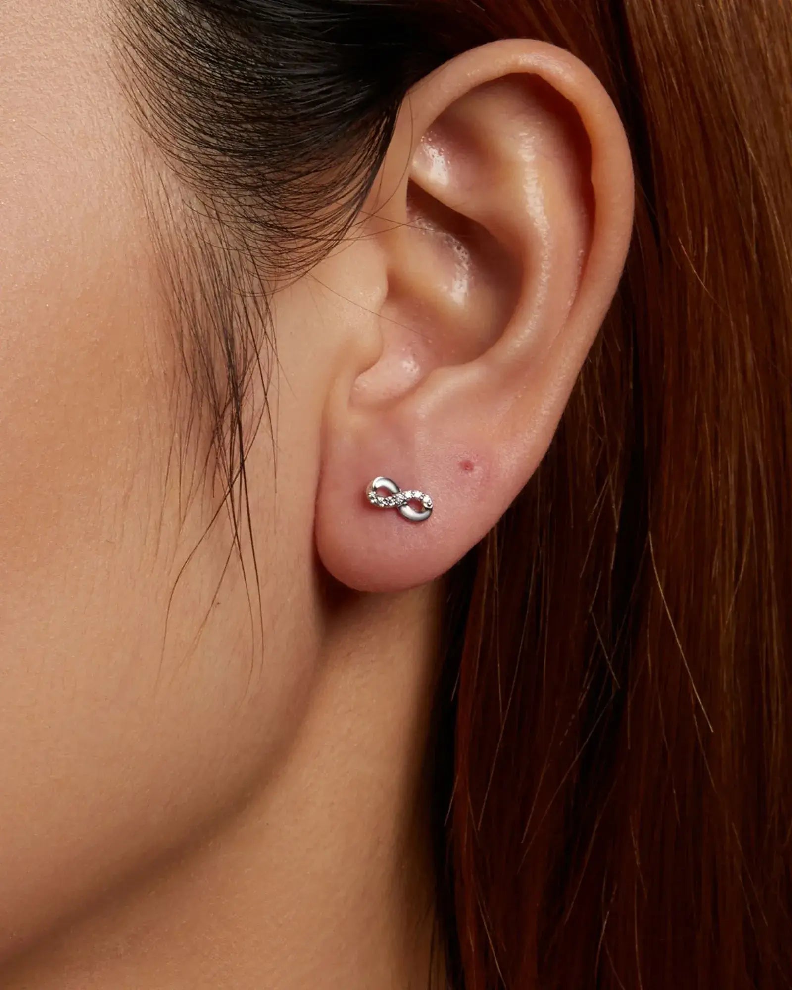 Elegant Infinity Ear Stud in 925 Sterling Silver and White Gold Plating with Moissanite Inlay, worn on ear.