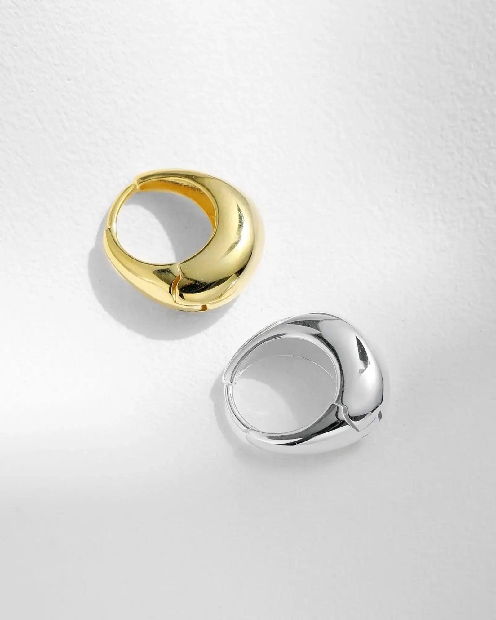 Irregular solid hoop earrings in gold and silver, showcasing unique sculptural designs and a high-polish finish.