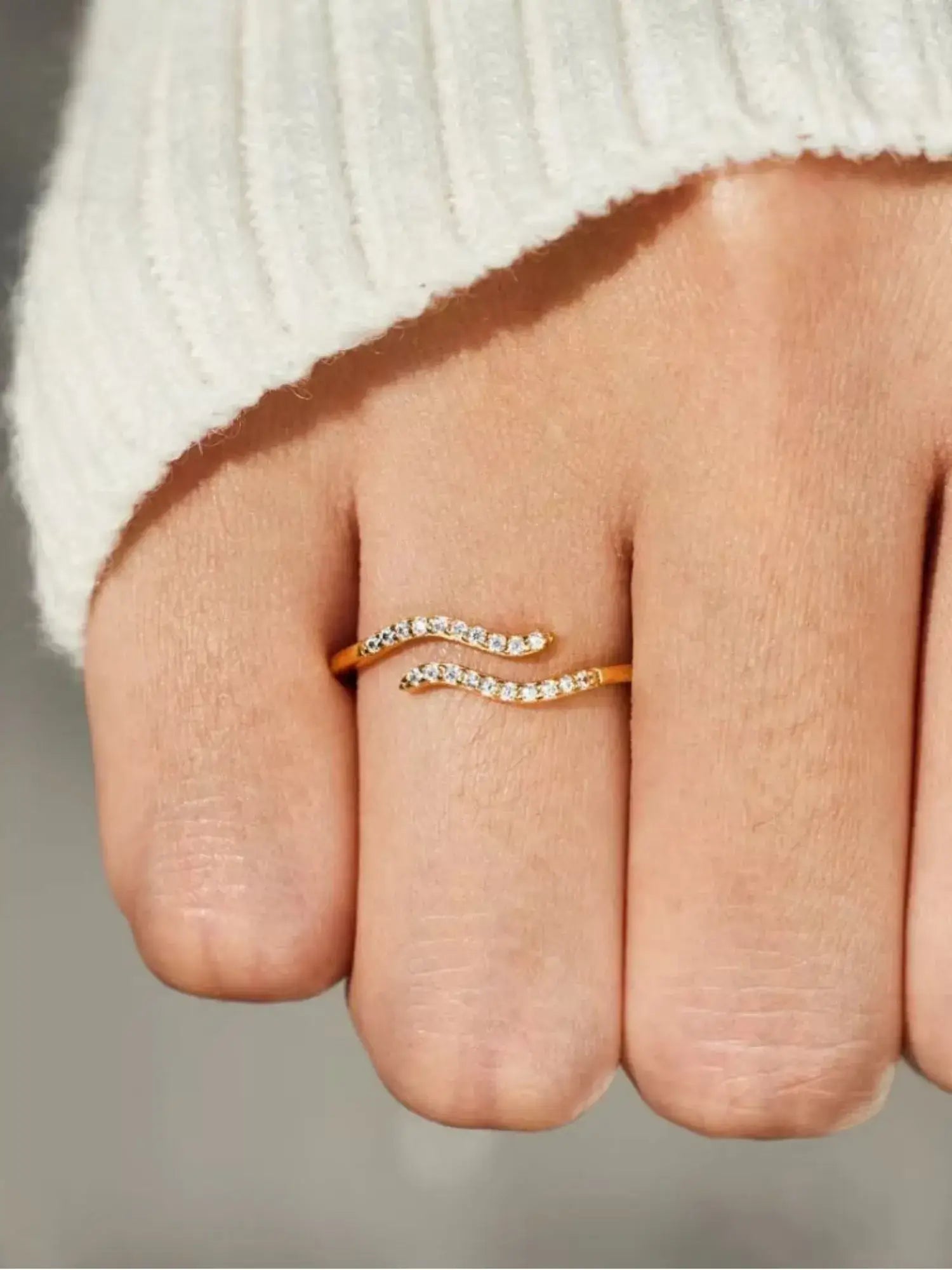 Minimalist single wave ring in 18k gold with pavé-set stones, showcasing a graceful design on a hand.