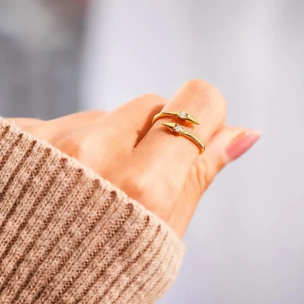 Open Arrow Ring in gold, featuring cubic zirconia, worn on a hand with a cozy sweater.