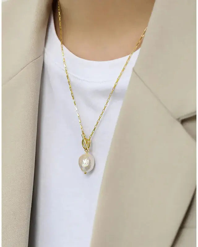 Single Pearl pendant necklace Lia worn on a model with an elegant beige coat and white t-shirt.
