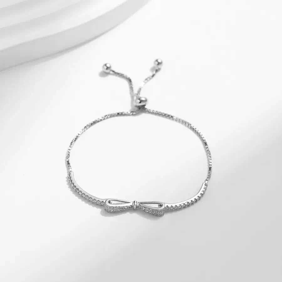 Adjustable sterling silver bow knot bracelet with pave-set zircon stones, perfect for elegant accessories.