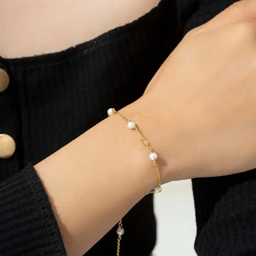 Vaire pearl bracelet in silver featuring lustrous pearls worn on a hand against a black sweater.