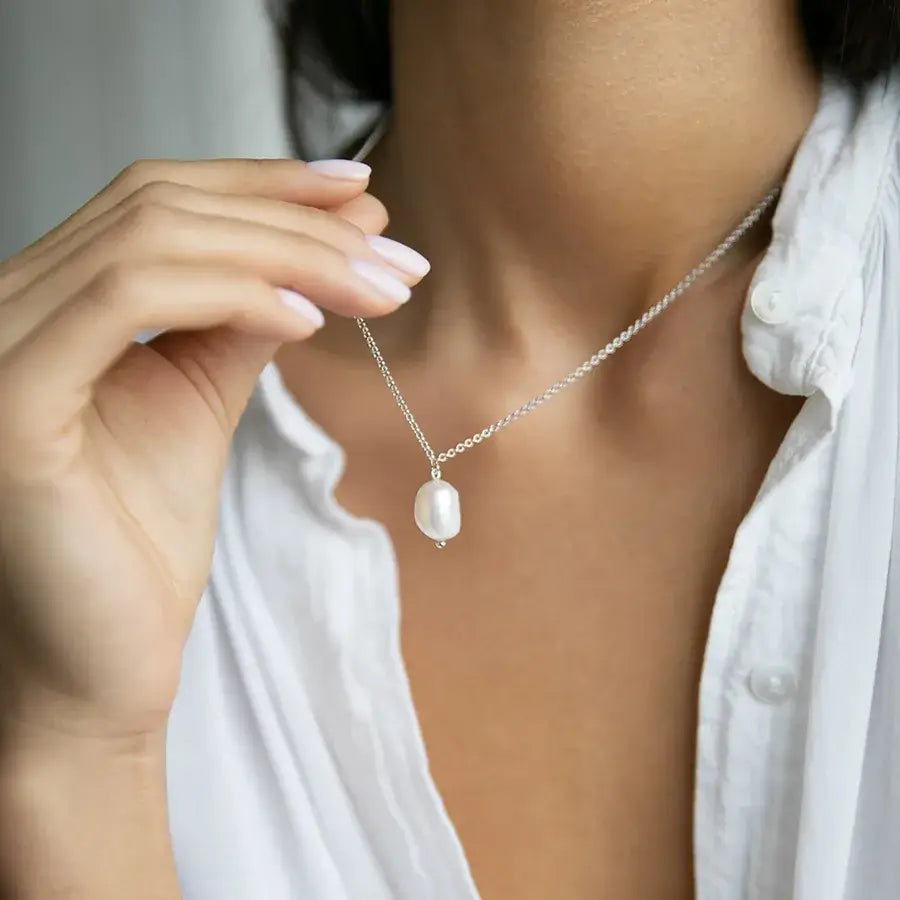 Close-up of a woman wearing a Lumera Pearl Pendant Necklace in sterling silver with white gold plating.