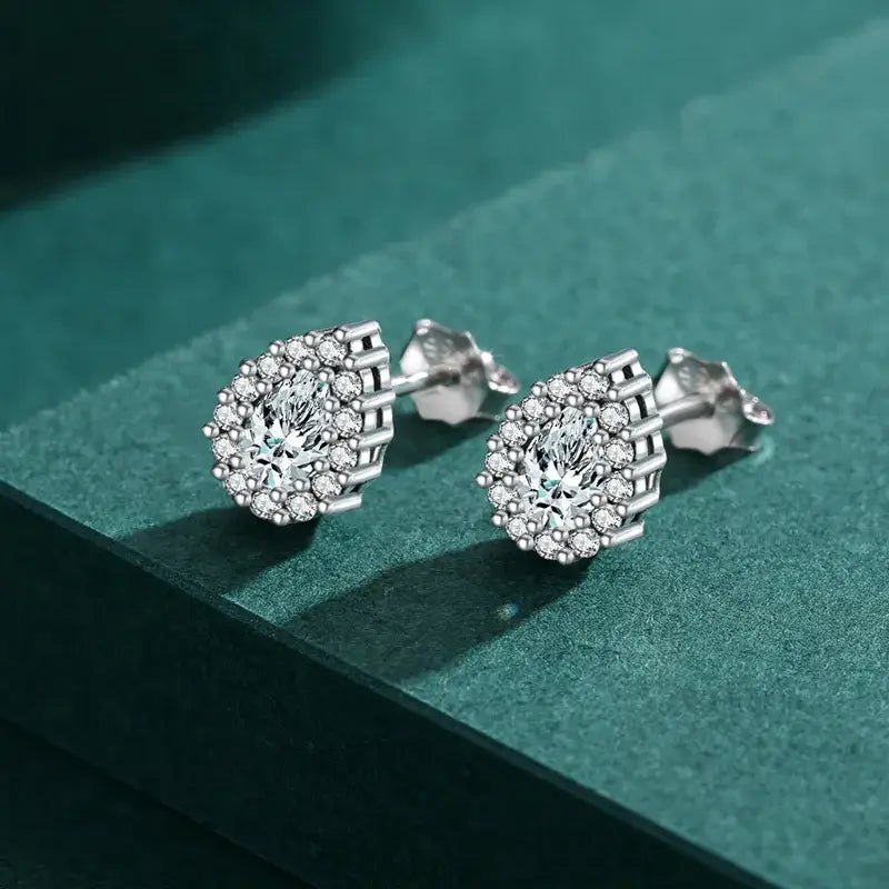 Sterling silver water droplets ear studs featuring a classic design and zircon inlay on a green surface.