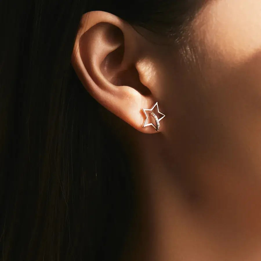 Hollow star Ear studs showcased in silver zircon inlay on a model's ear.