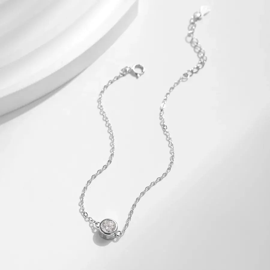 0.5 ct moissanite halo bracelet on a white background with a sterling silver chain and bezel-set moissanite.