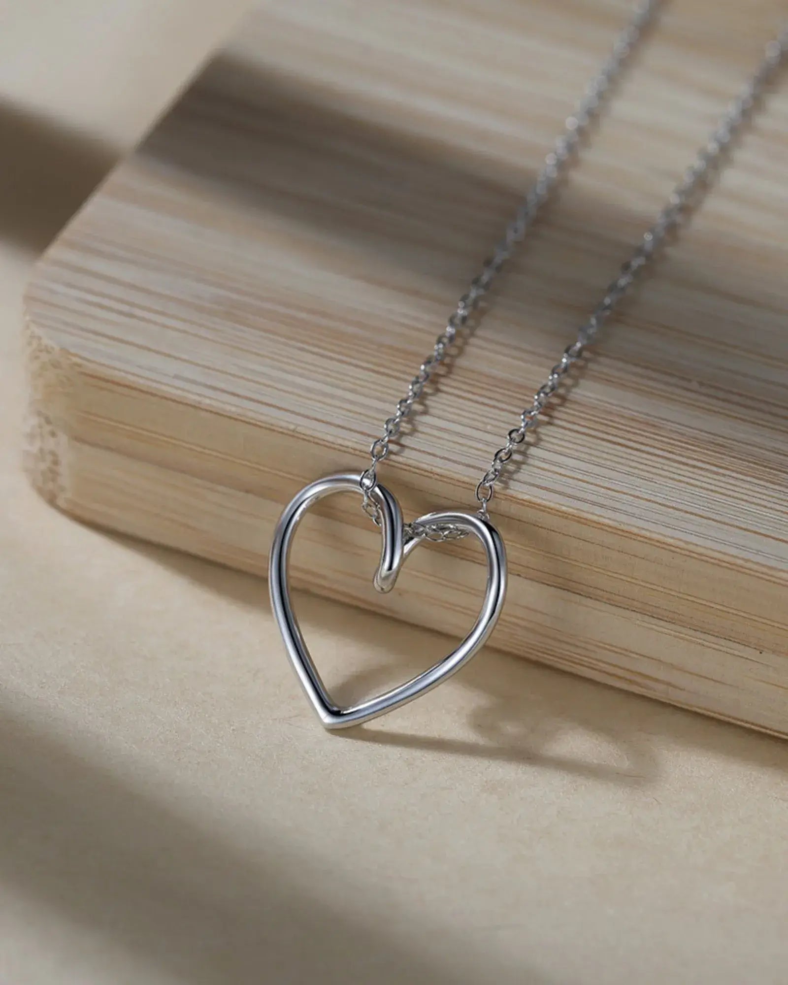 True Heart Pendant Necklace in polished 925 sterling silver, featured on a wooden background.