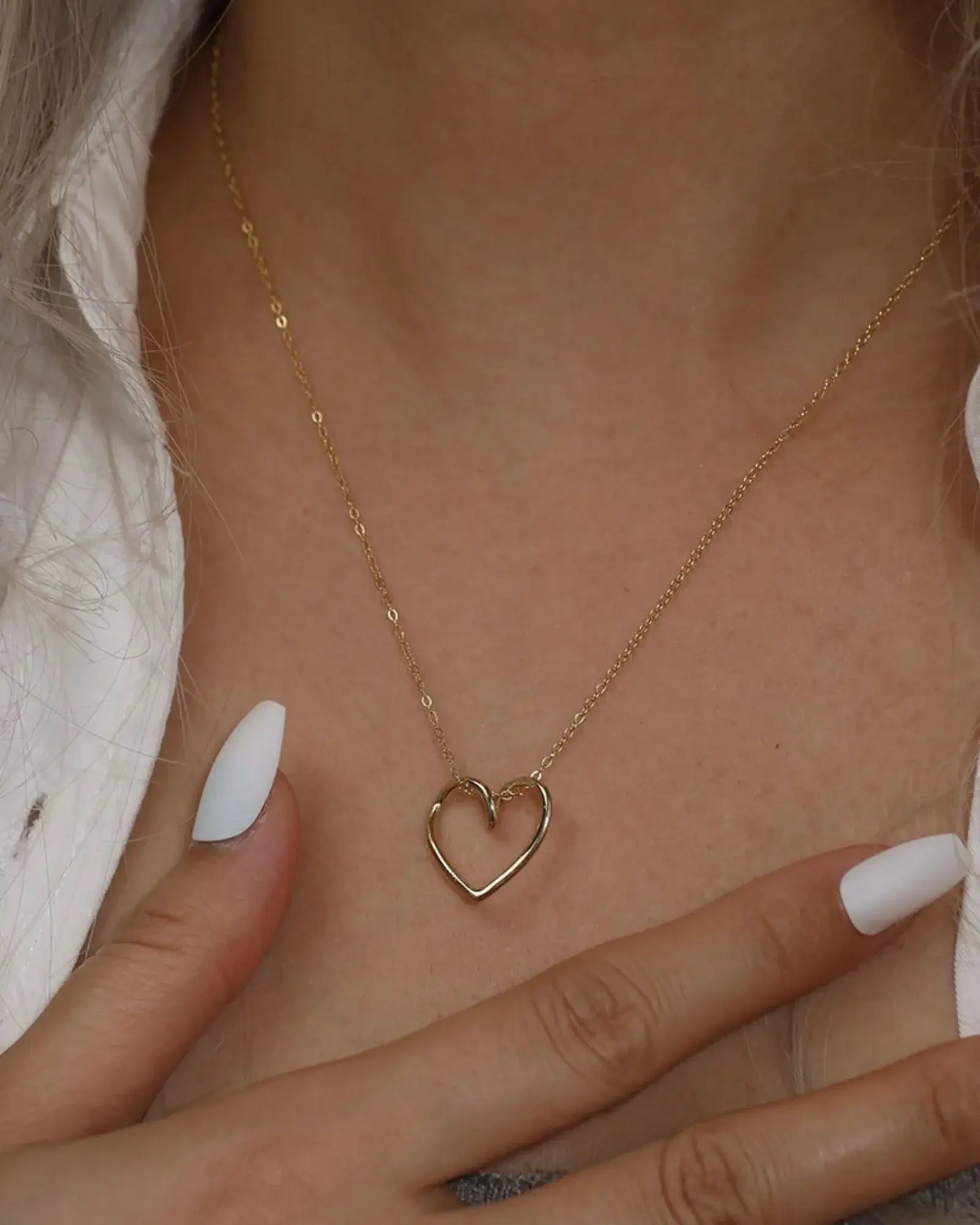 Gold heart pendant necklace on model, featuring a refined design and delicate chain.