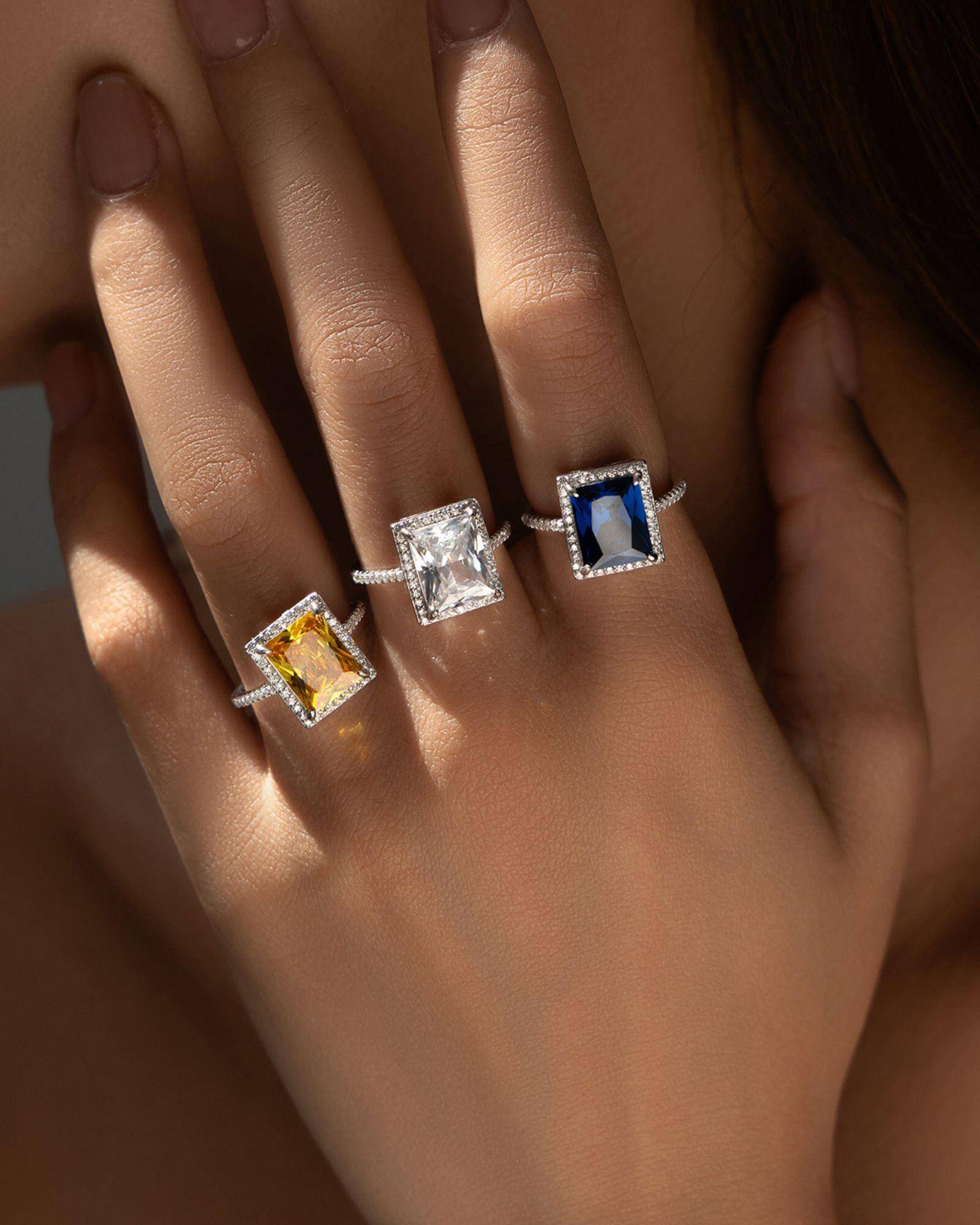 Elegant cocktail rings featuring yellow zirconia, clear zircon, and blue gemstones, showcased on a model's hand.