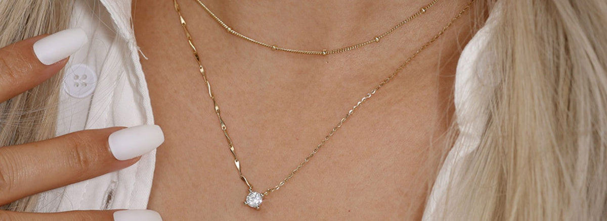 Minimalist jewellery for any occasion featuring layered gold necklaces and a sparkling pendant.