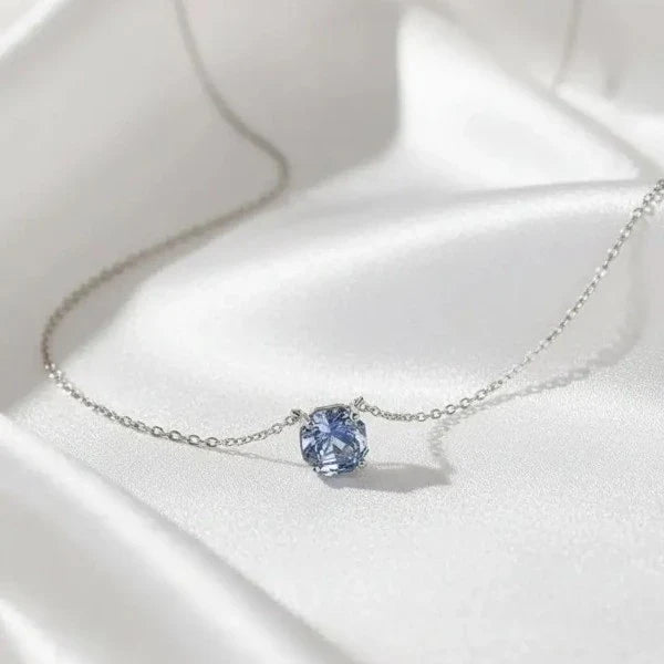 dainty blue stone pendant necklace on a satin fabric 