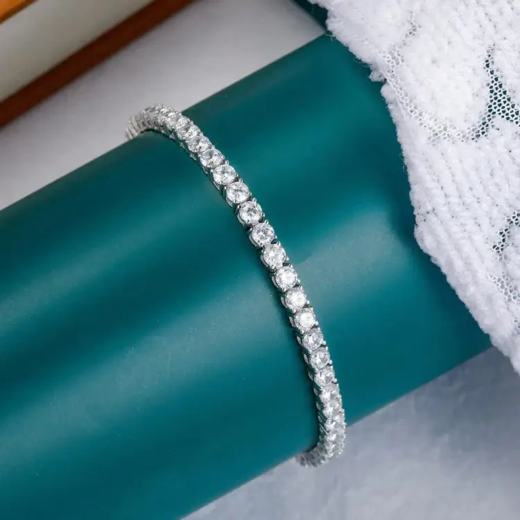 Elegant silver bracelet with sparkling gems showcased on a teal surface, perfect for trendy accessory collections.